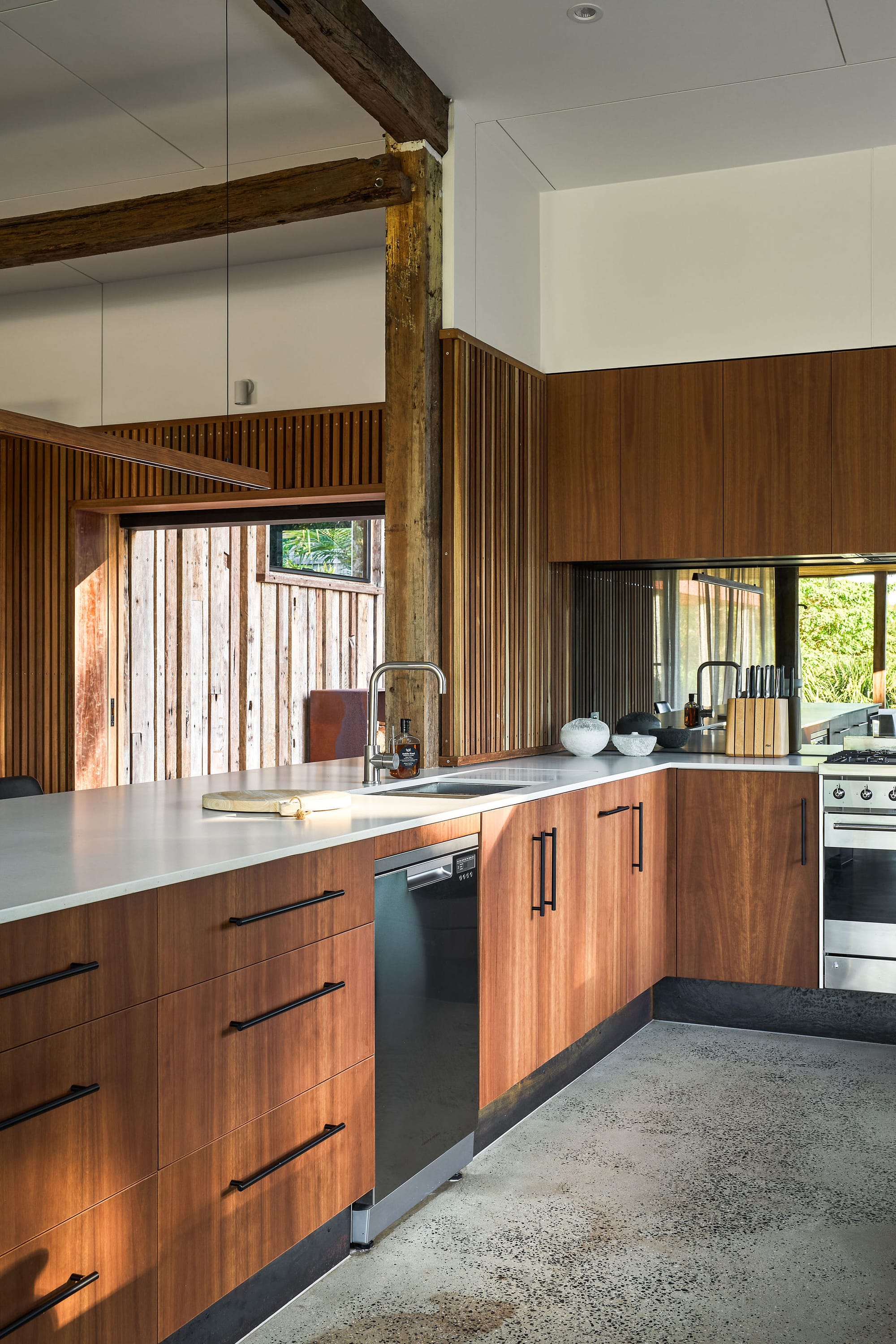 Rockpool Farm Byron Bay. Photography by Andy Macpherson. Timber veneer kitchen counters and polished concrete floors. Timber clad walls. White countertops. Exposed timber beams below white ceiling. 