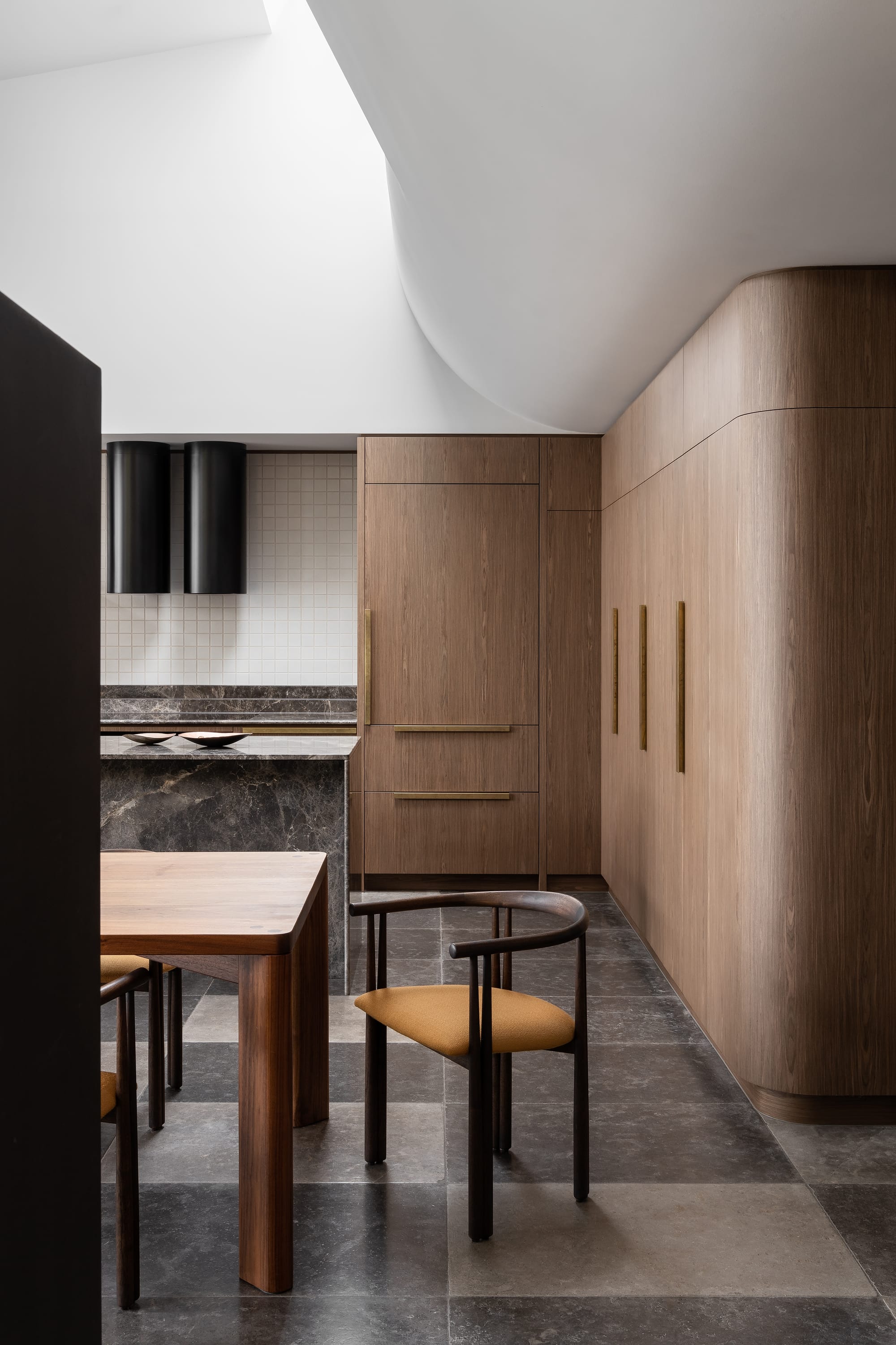 Rose Park by studio gram. Photography by Timothy Ross. Residential kitchen with checkerboard stone floors. Timber cabinetry with curved edges. Grey granite counters and countertops. White tile splashback. 