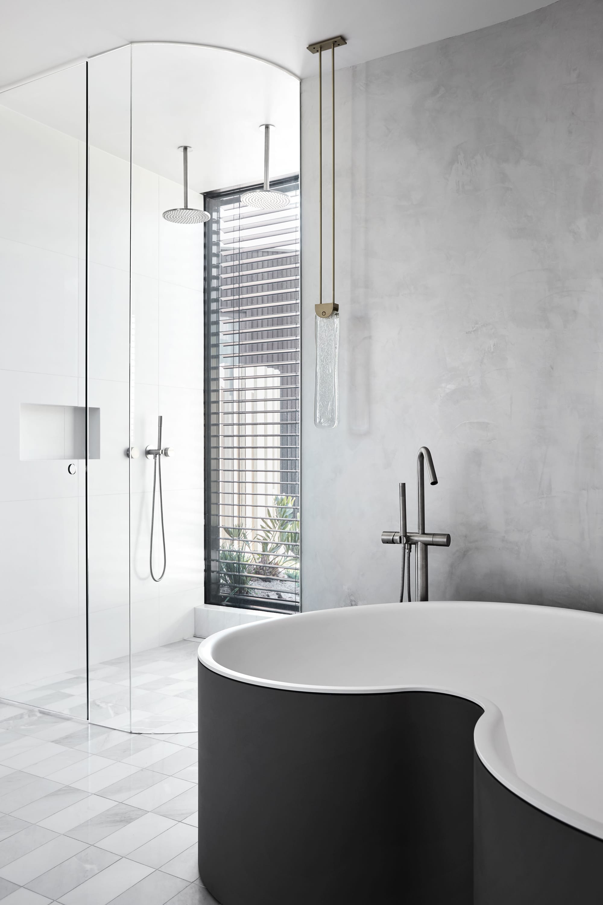 The Split Home by Seidler Group. Copyright of Seidler Group. Interior bathroom with black, curved tub. Large shower in back left corner. Various grey tiles from floor to ceiling. 