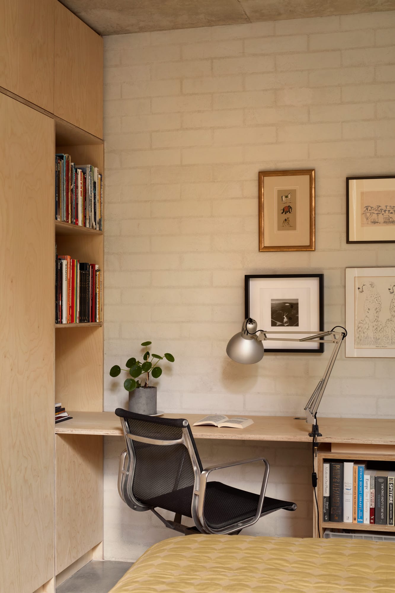 Brick House by Studio Roam. Photography by Jack Lovel. Study space with plywood desk and shelving to left. White brick wall. Black and chrome desk chair. 