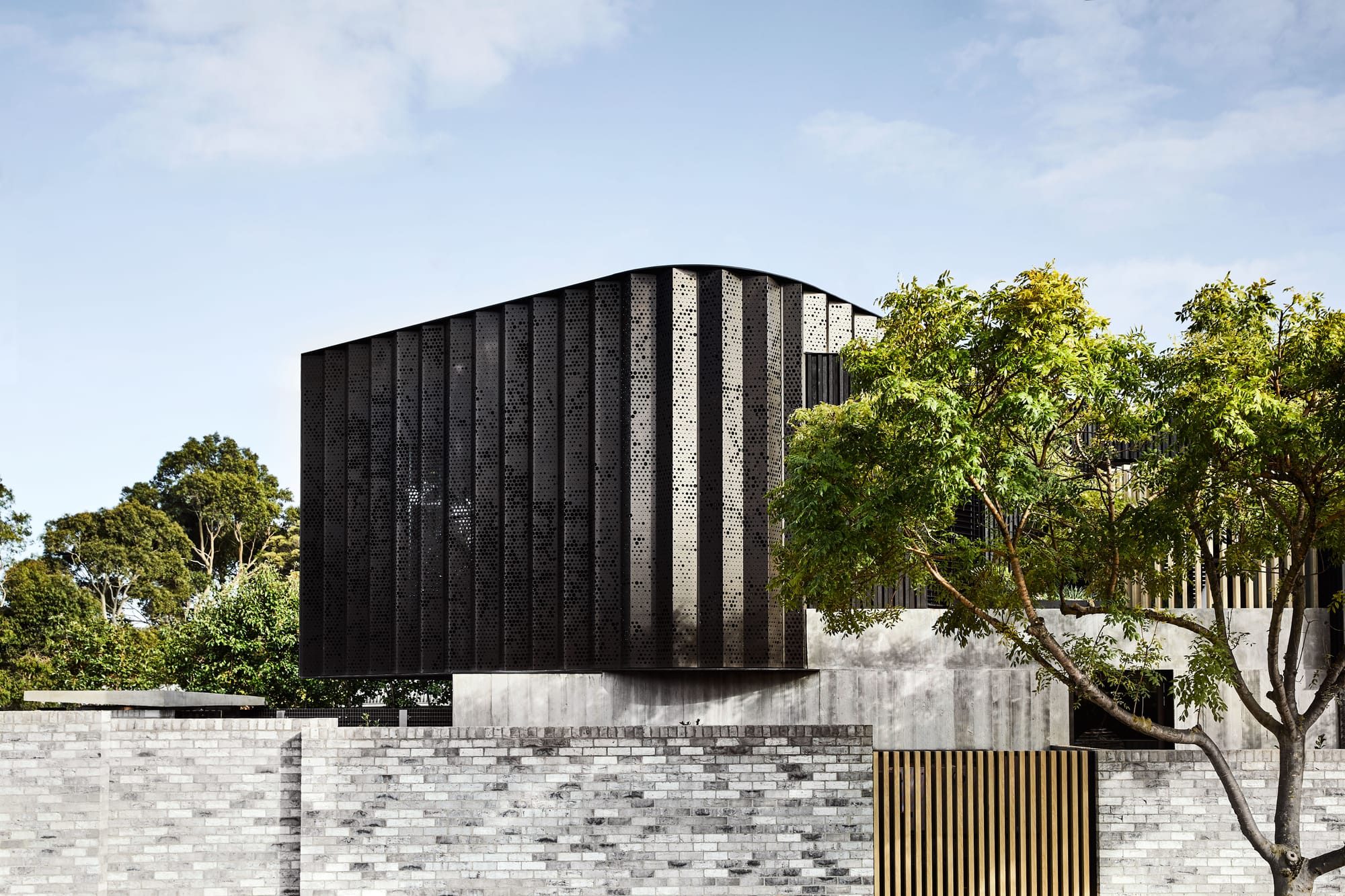 The Split Home by Seidler Group. Copyright of Seidler Group. Street facade of double storey, co temporary home. Brick and timber fence. Black metal second storey. 