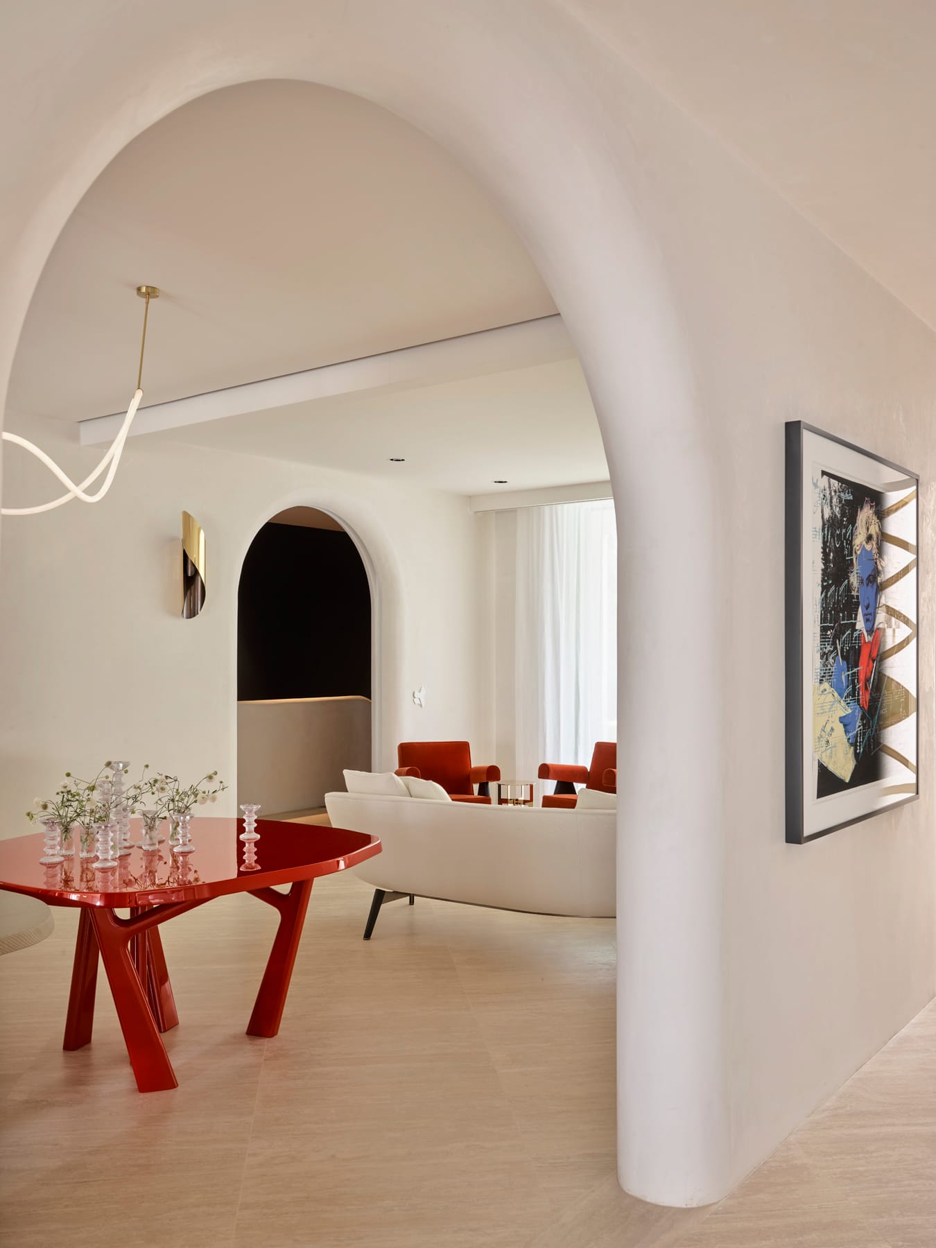 Toorak House 2 by K.P.D.O. Photography by Sharyn Cairns. Large archway leading to sitting room. Red table. White couch and red armchairs. White plaster walls. 