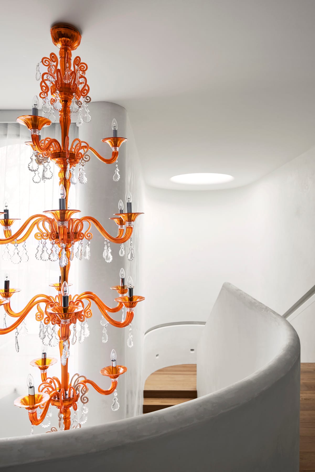 Toorak House 2 by K.P.D.O. Photography by Sharyn Cairns. Orange tiered glass chandelier hanging in stairwell. Curved white balustrade. 