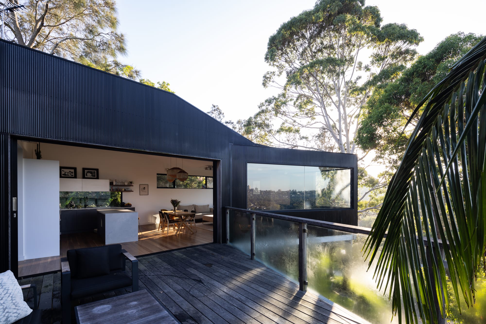 Tree House by North By North. Photography by Simon Whitbread. Timber deck extending out from kitchen and dining. Black timber clad exterior. 