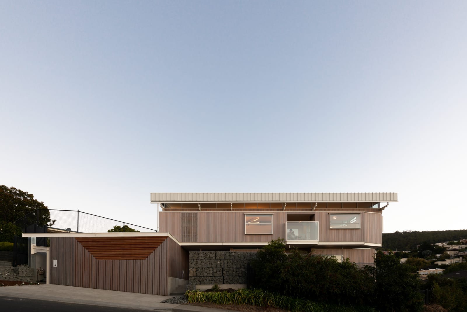Wattle Bird House by Flett Architecture. Photography by Matt Sansom. Timber clad facade of double storey home. Rolling hills in background.