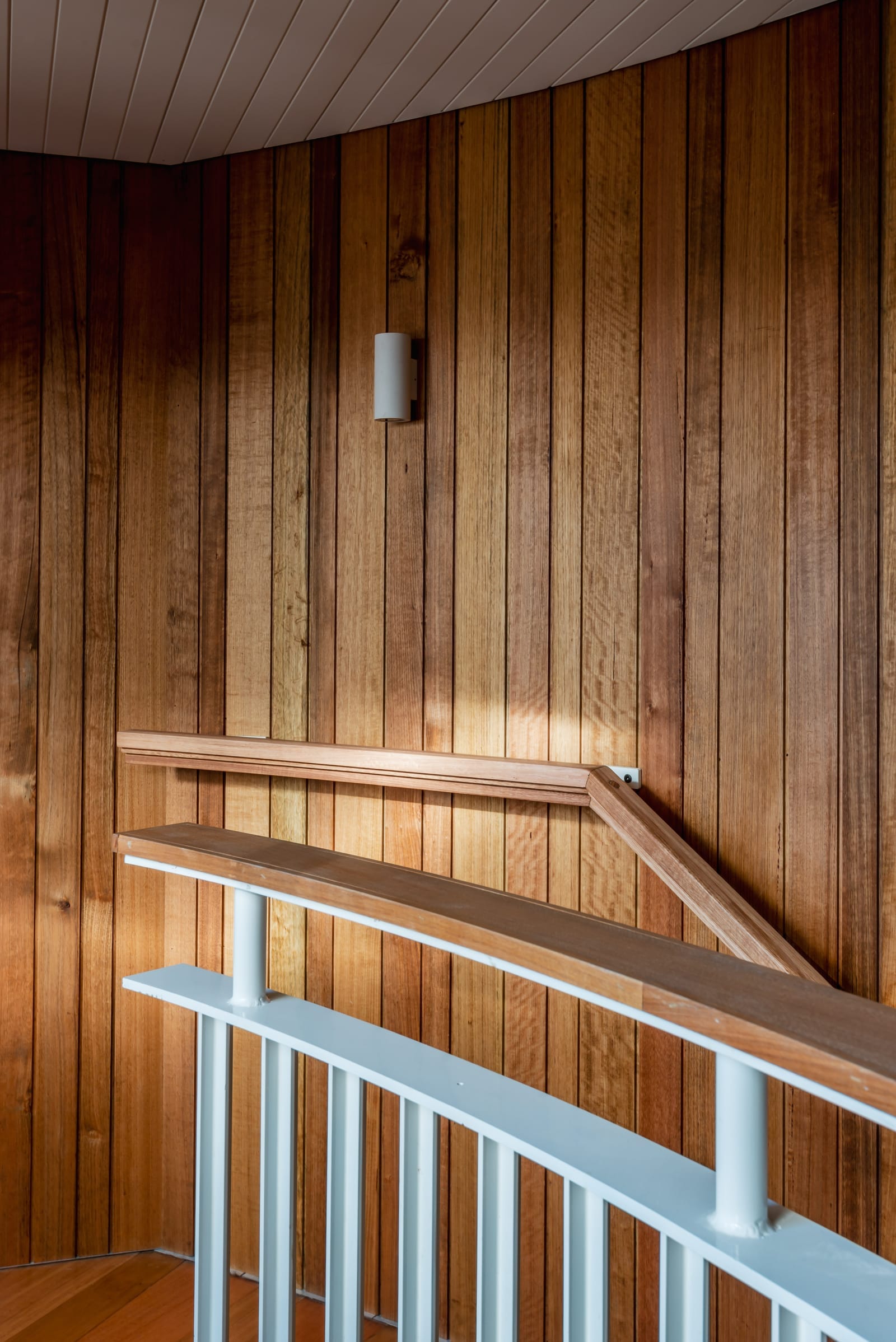 Wattle Bird House by Flett Architecture. Photography by Matt Sansom. Timber and metal balustrade in front of timber paneled wall and timber floor. 