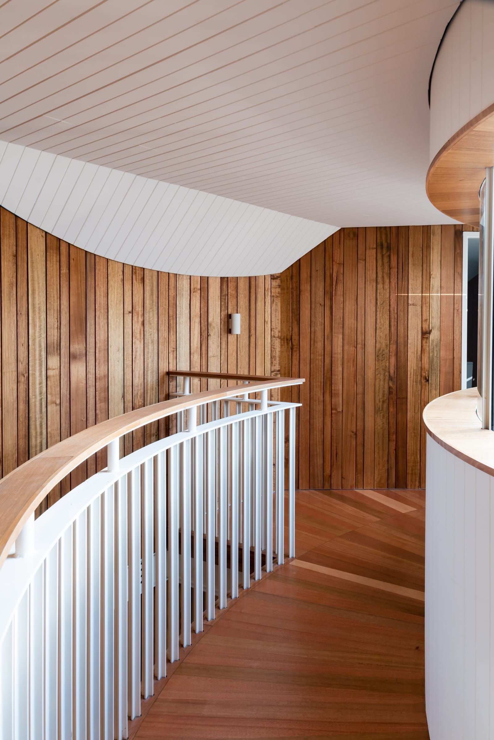 Wattle Bird House by Flett Architecture. Photography by Matt Sansom. Curved timber staircase with white metal and timber balustrade. Timber floors and walls.