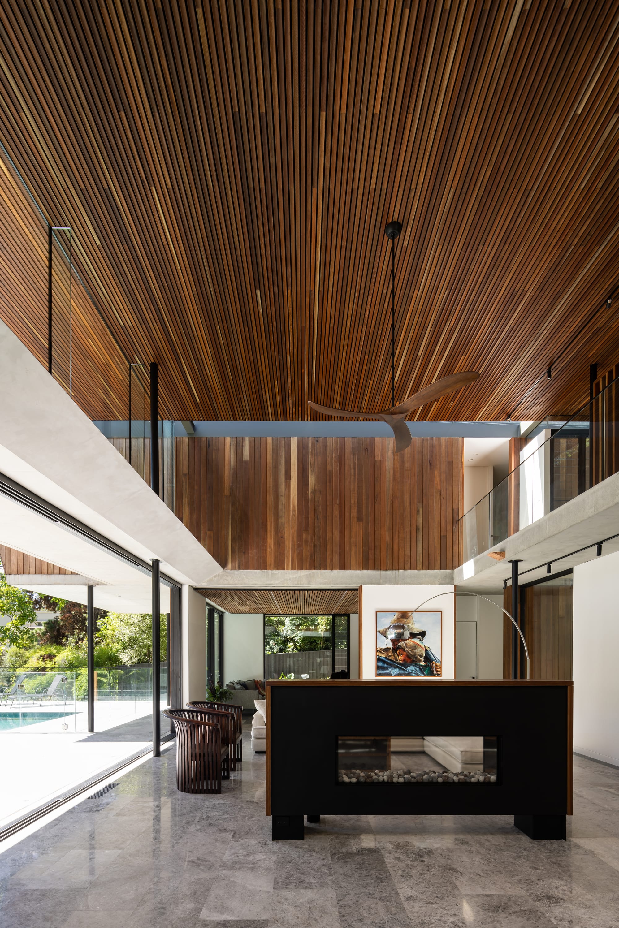 Mortlock Timbers Series: Fox Valley House. Photography by Simon Whitbread. Double heigh living space with floor-to-ceiling glass windows overlooking verandah and pool to the left. Timber clad walls and ceiling on second floor. 