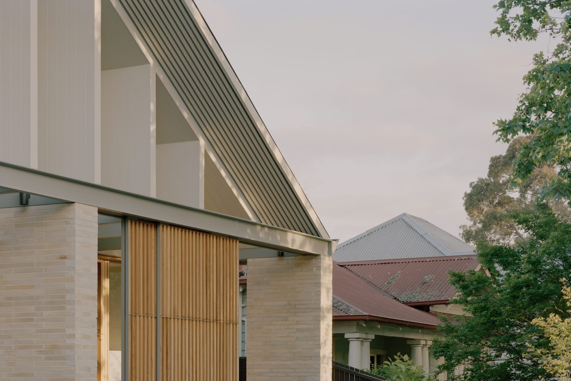 Gable Park by Weaver+Co Architects. Photography by Tasha Tylee. Roof profile of double storey home. Pitched roof with white timber supports. Timber clad screen wall on ground floor and brick pillars. 
