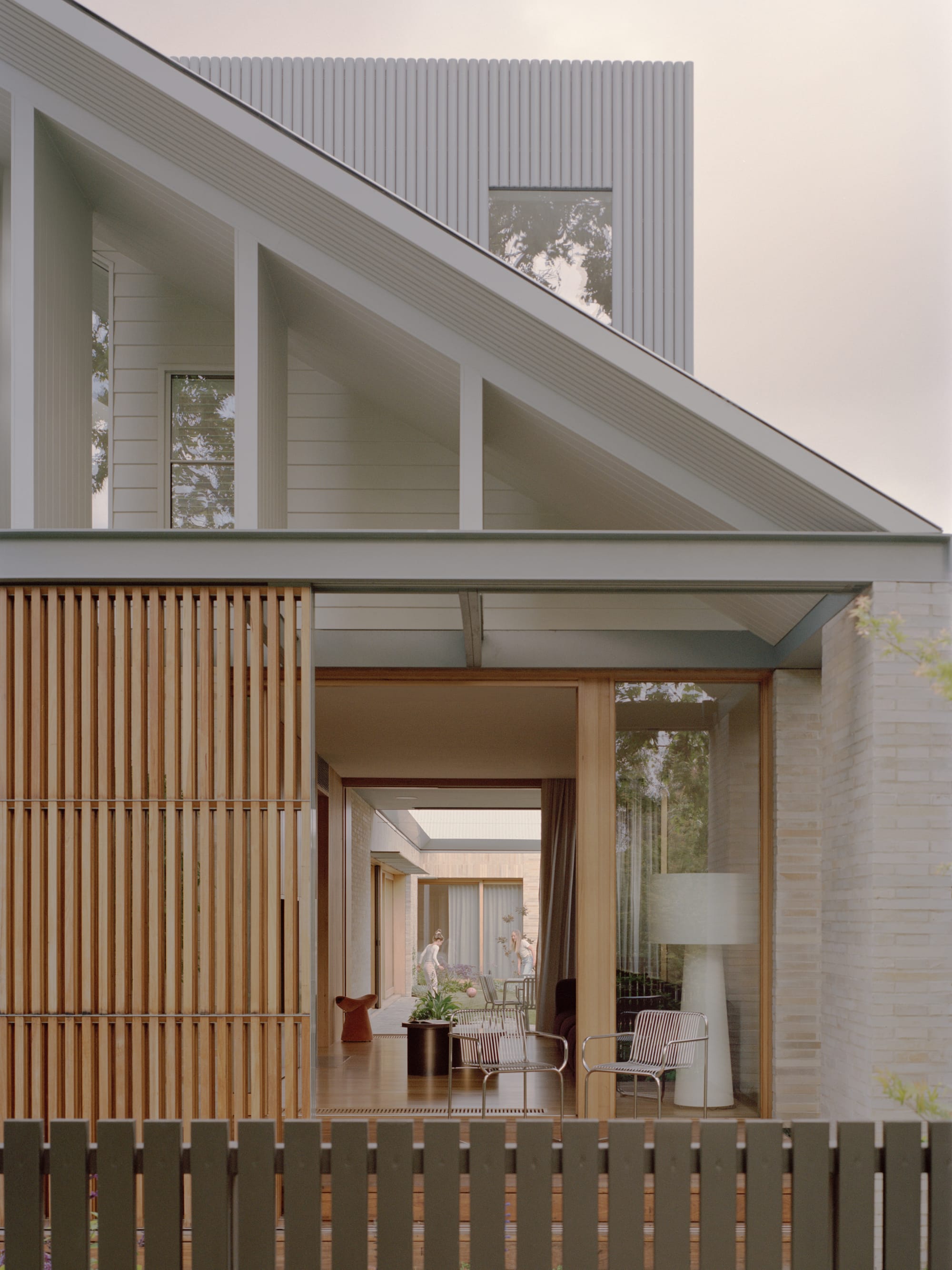 Gable Park by Weaver+Co Architects. Photography by Tasha Tylee. Facade of home with timber screening and open plan living. Courtyard visible through living space. Pitched roof. 