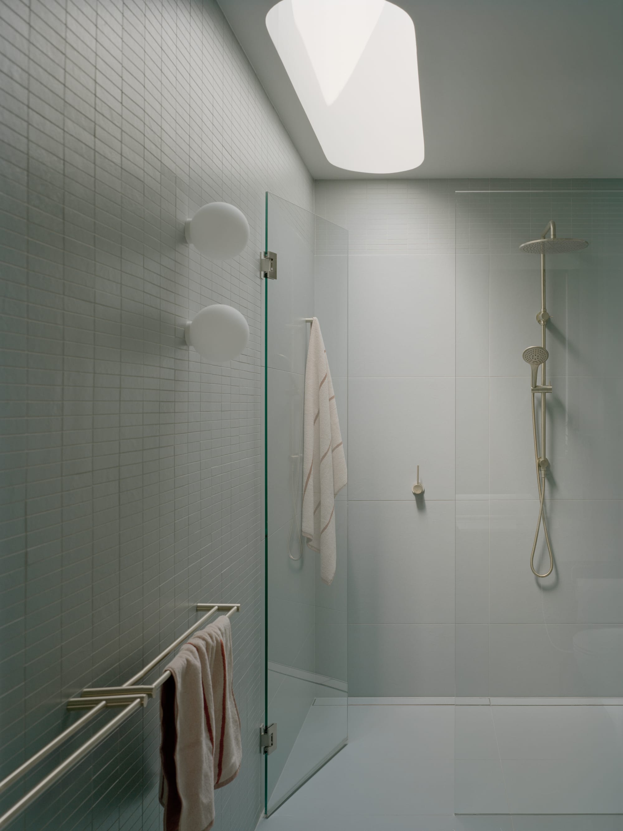 Gable Park by Weaver+Co Architects. Photography by Tasha Tylee. White tiled bathroom with glass shower and skylight. 