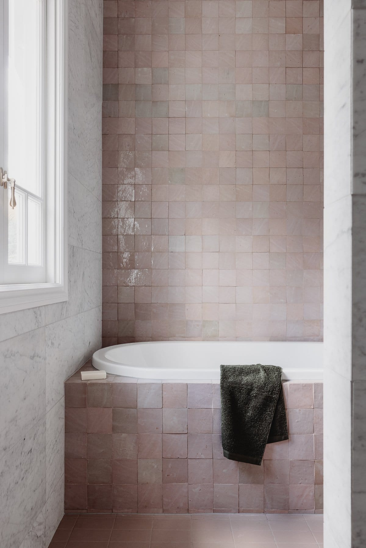 Hazlewood House by Favell Architects. Photography by Andy Macpherson. Bath surrounded by pink tiles. White marble tiles on wall and pink tiles on floor and wall behind bath.
