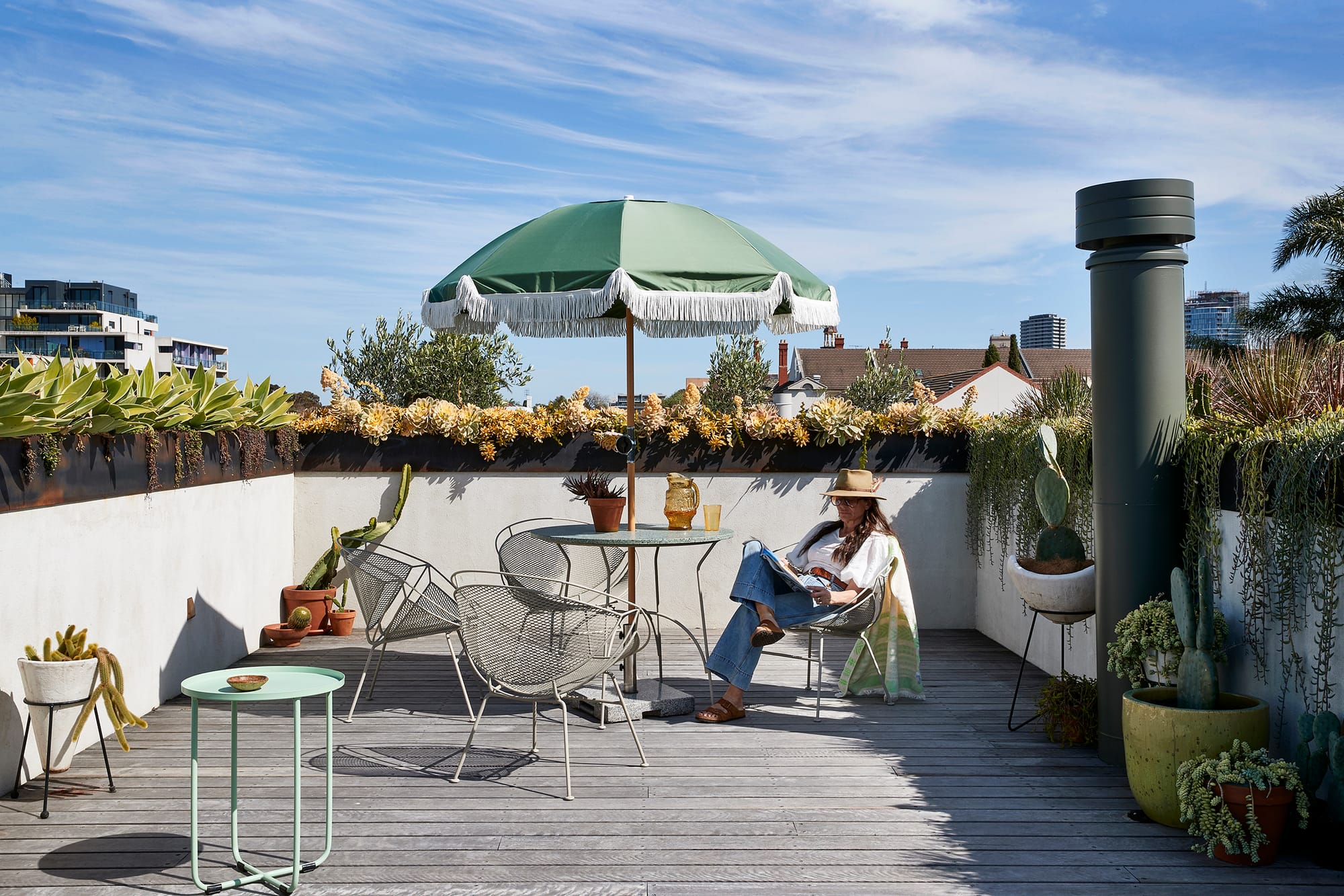 Fabrica by mcmahon and nerlich. Photography by Shannon McGrath. Rooftop terrace with weathered timber floors and white plastered half wall, topped with steel planters. Table with umbrella.
