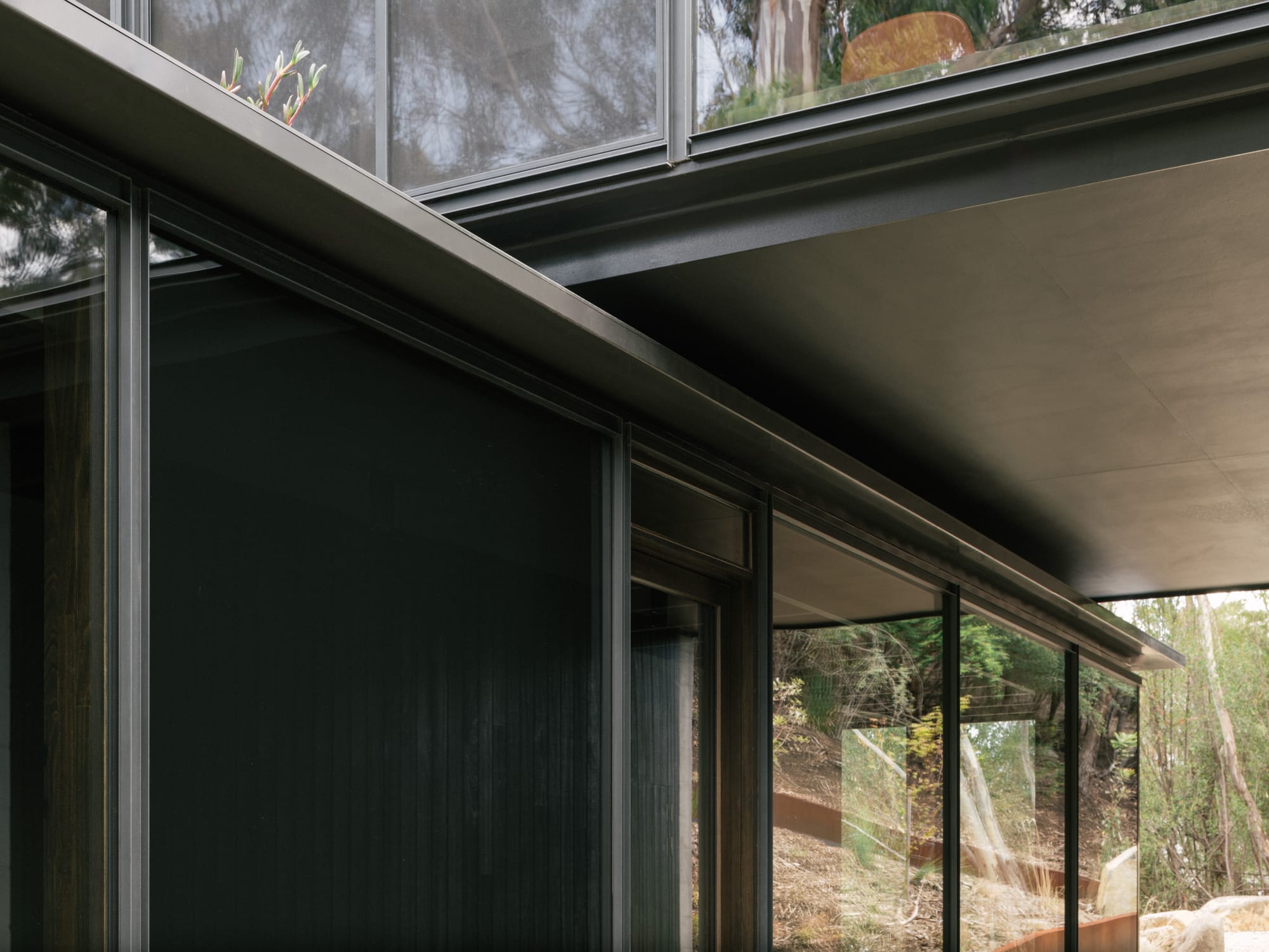 Taroona House by Archier. Photography by Thurston Empson. Close up shot of join between two separate rectangular structures made of timber and metal.