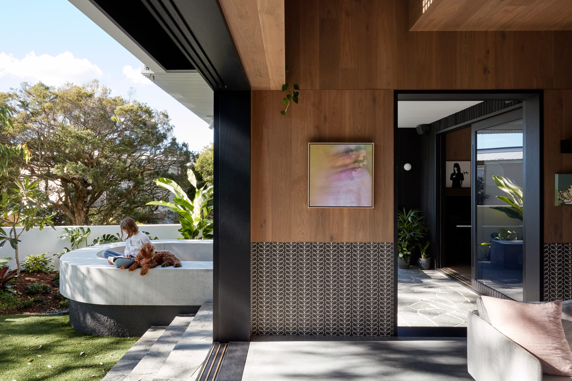 Uxbridge House by Tim Stewart Architects. Photography by Christopher Frederick Jones. Floor to ceiling door opening leading from interior of home to garden. Wood paneled walls inside. Green grass and cement half wall outside. 