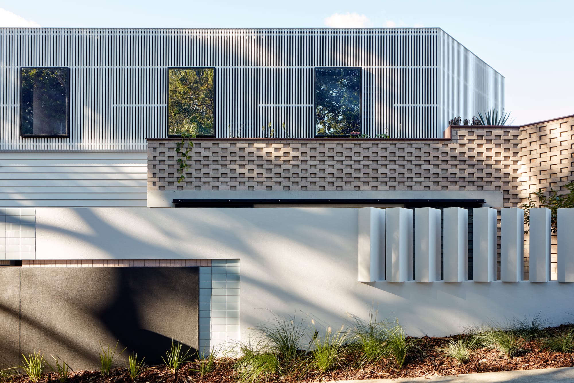 Uxbridge House by Tim Stewart Architects. Photography by Christopher Frederick Jones. Exterior of double story home with white render fence and garden bed at front. 