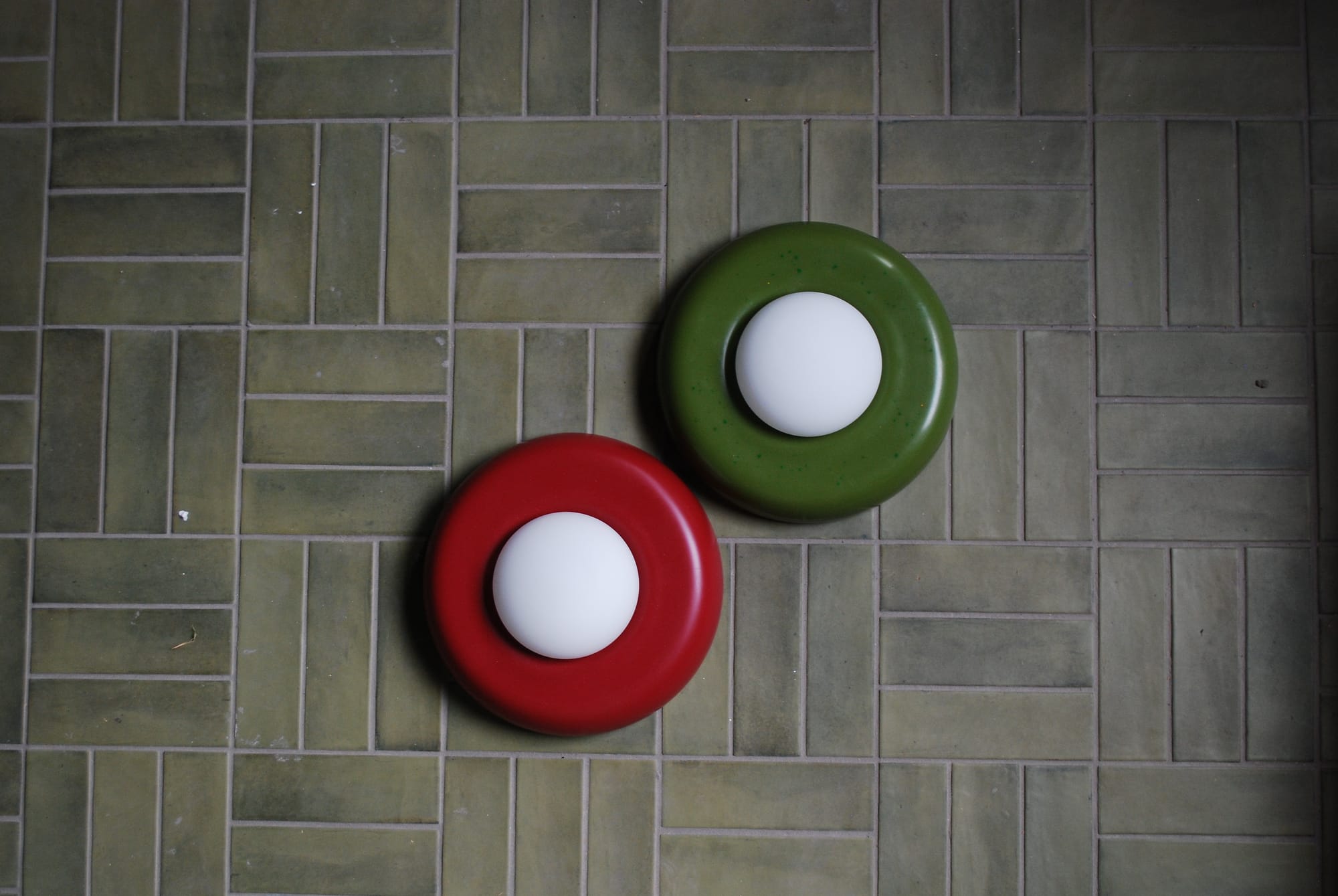ChromaBlock Wall Sconces in red and green on a green tile wall