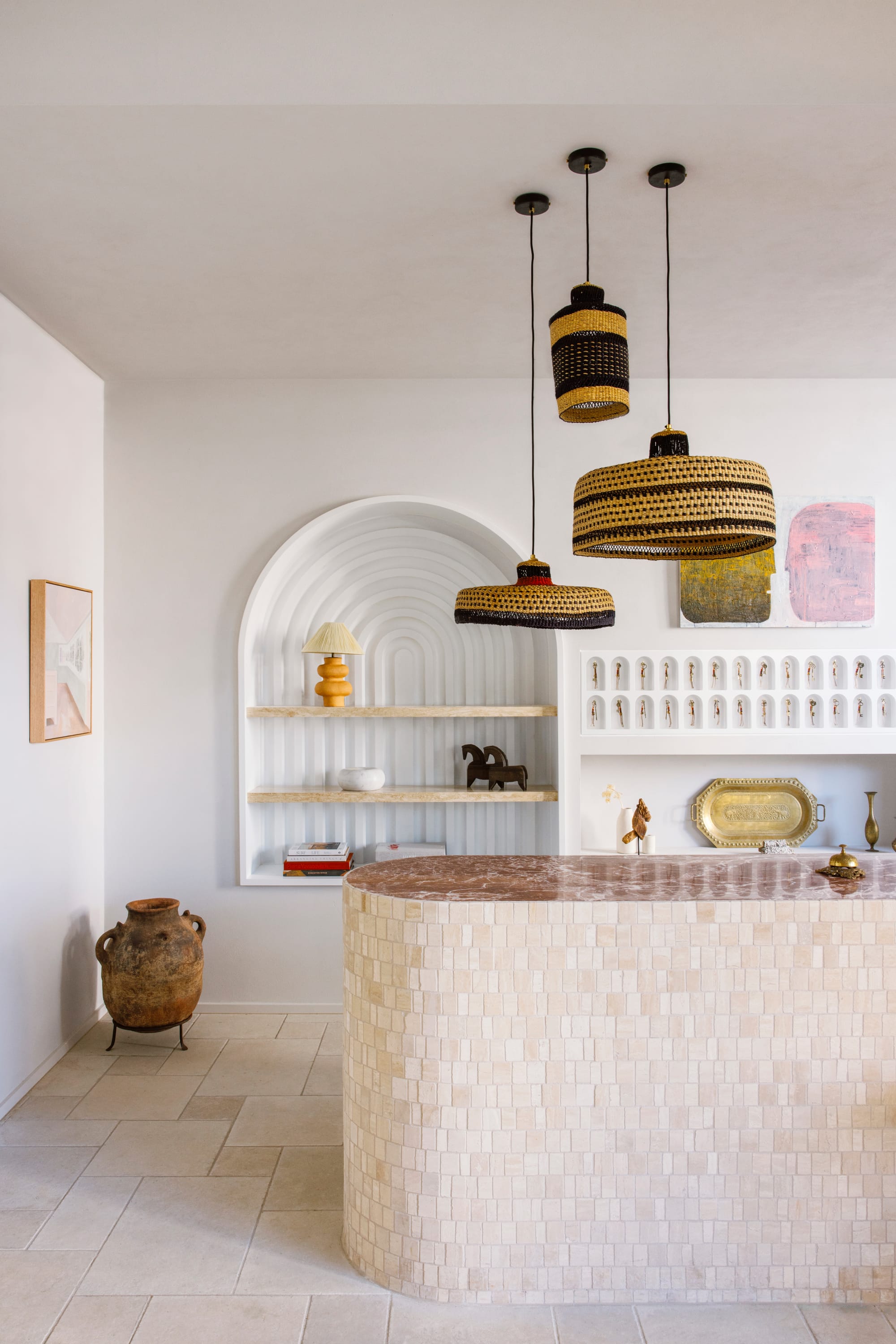 Basq House. Photography by Elise Hassey. Hotel reception with tiled and curved front desk and neutral floor tiles. Curved white integrated storage on walls.