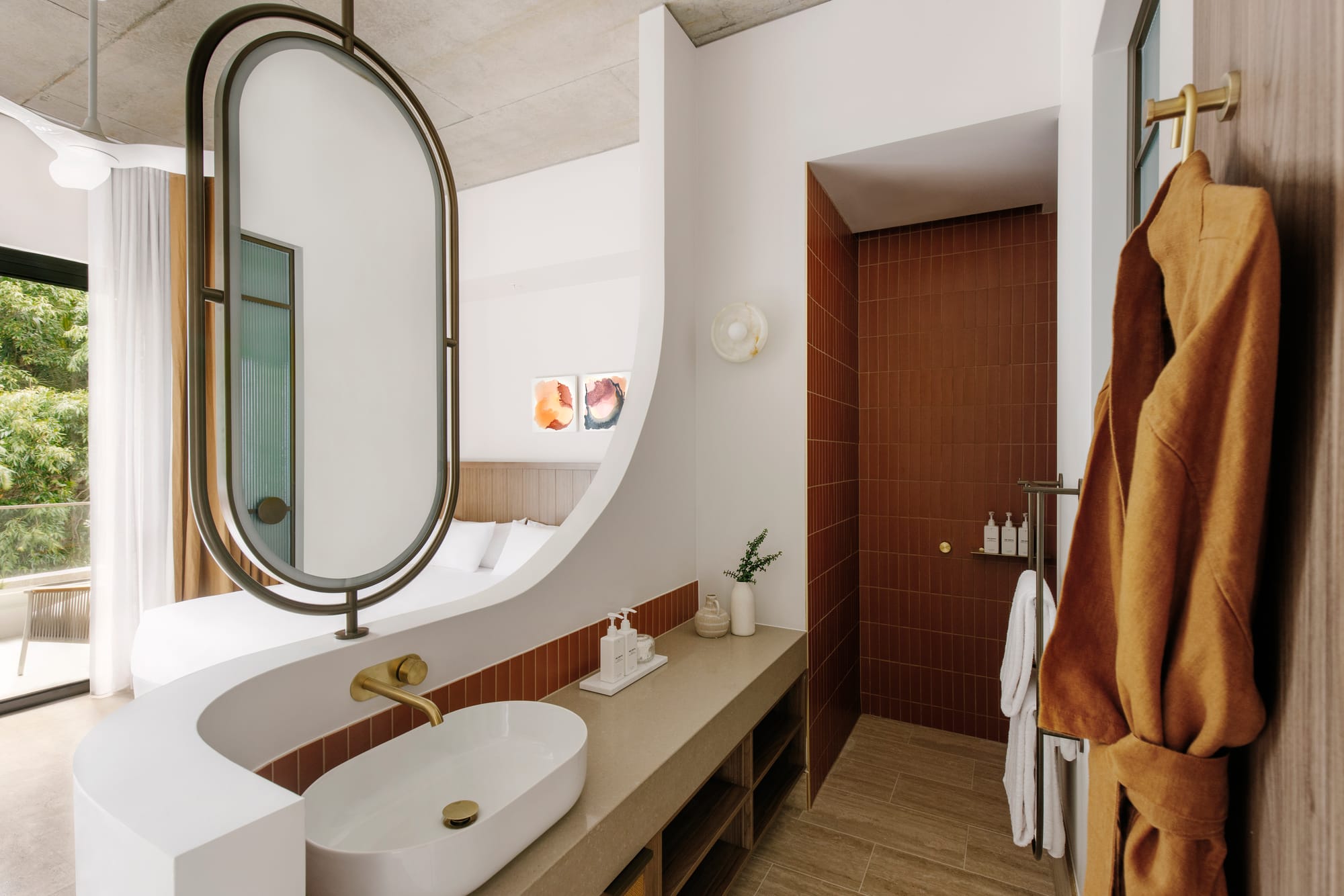 An interior shot of the hotel room at BASQ House showing the open ensuite with a feature mirror and an orange robe hanging up