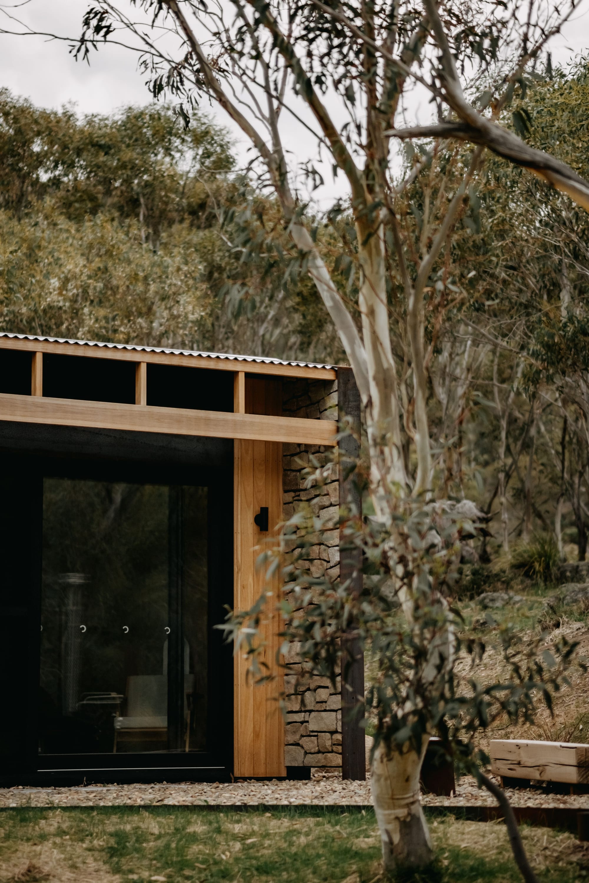 Crafters Eco-Cabins. Image copyright of Crafters. Eucalyptus tree in foreground, timber clad cabin with stonework in background.
