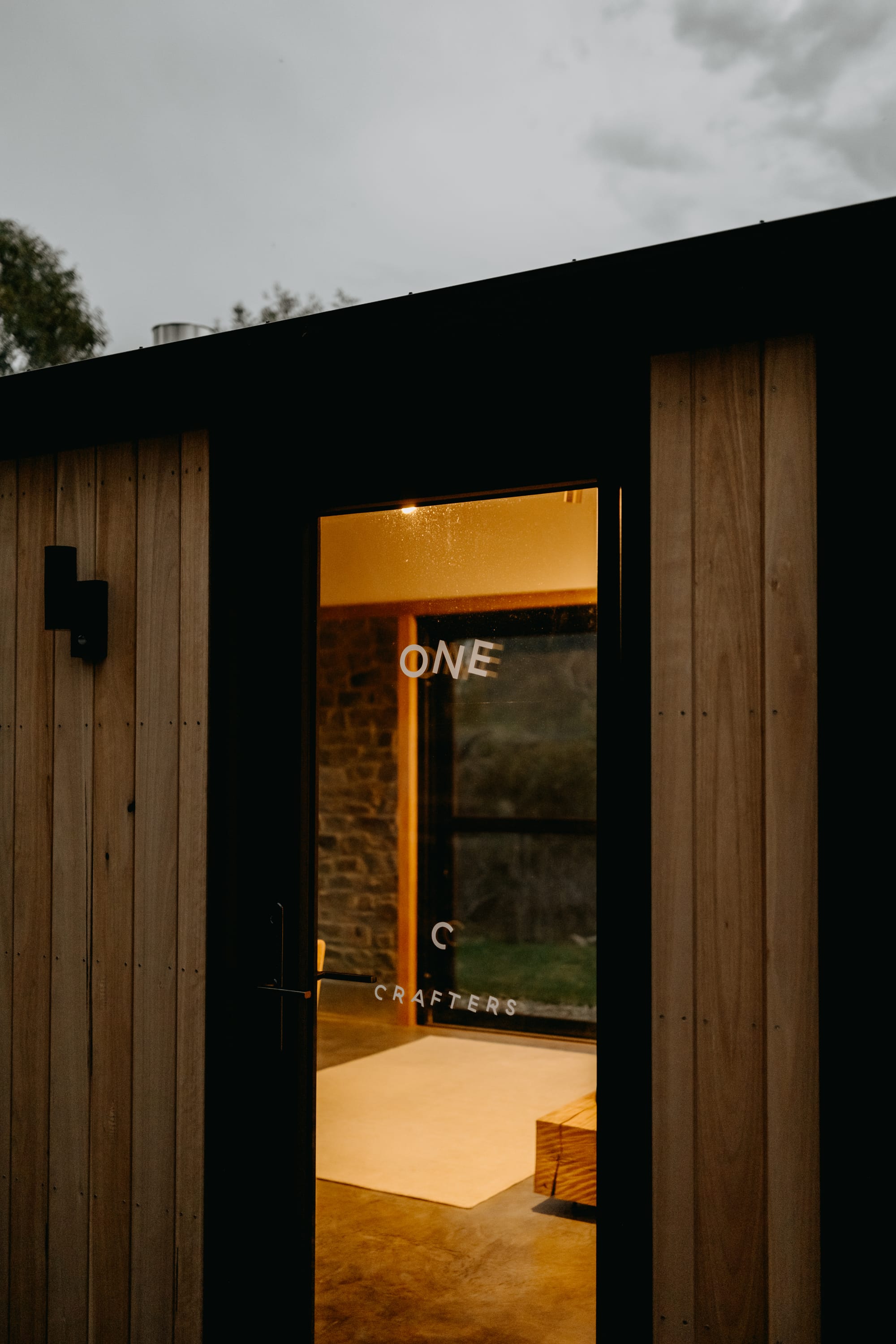 Crafters Eco-Cabins. Image copyright of Crafters. Glass door with white text font. Woooden clad walls.