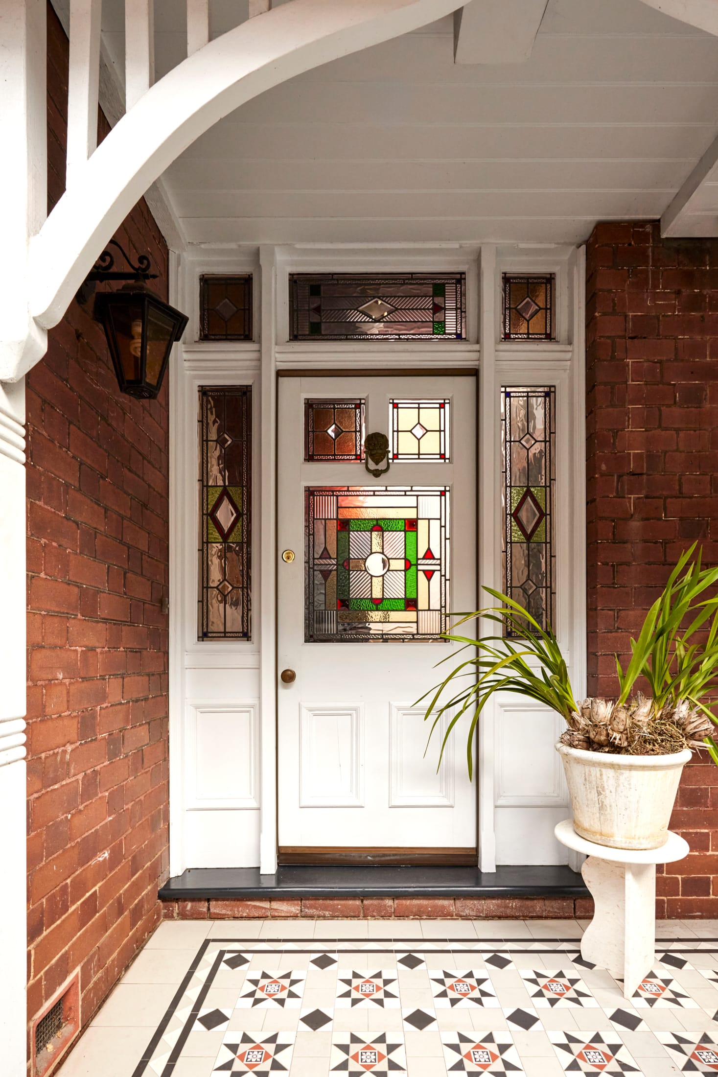 Drummoyne House by studio BARBARA. Photography by Jacqui Turk. White front door with stained glass details and heritage floor tiling. Red brick facade.