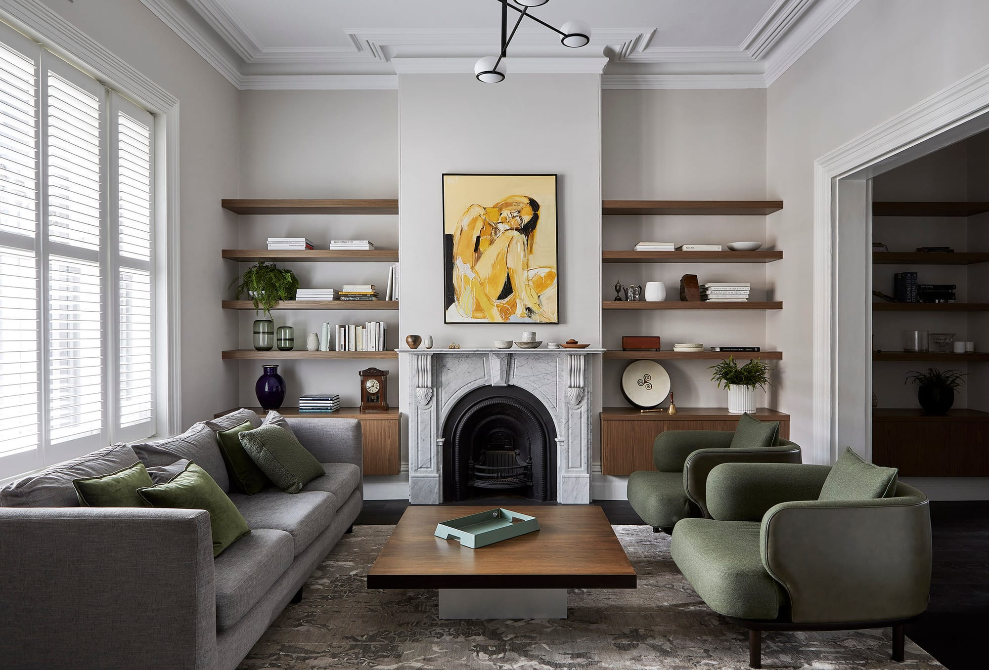 Village Studio by mcmahon and nerlich. Photography by Dave Kulesza. Marble fireplace, grey and green couch and armchairs. Floating timber shelves.