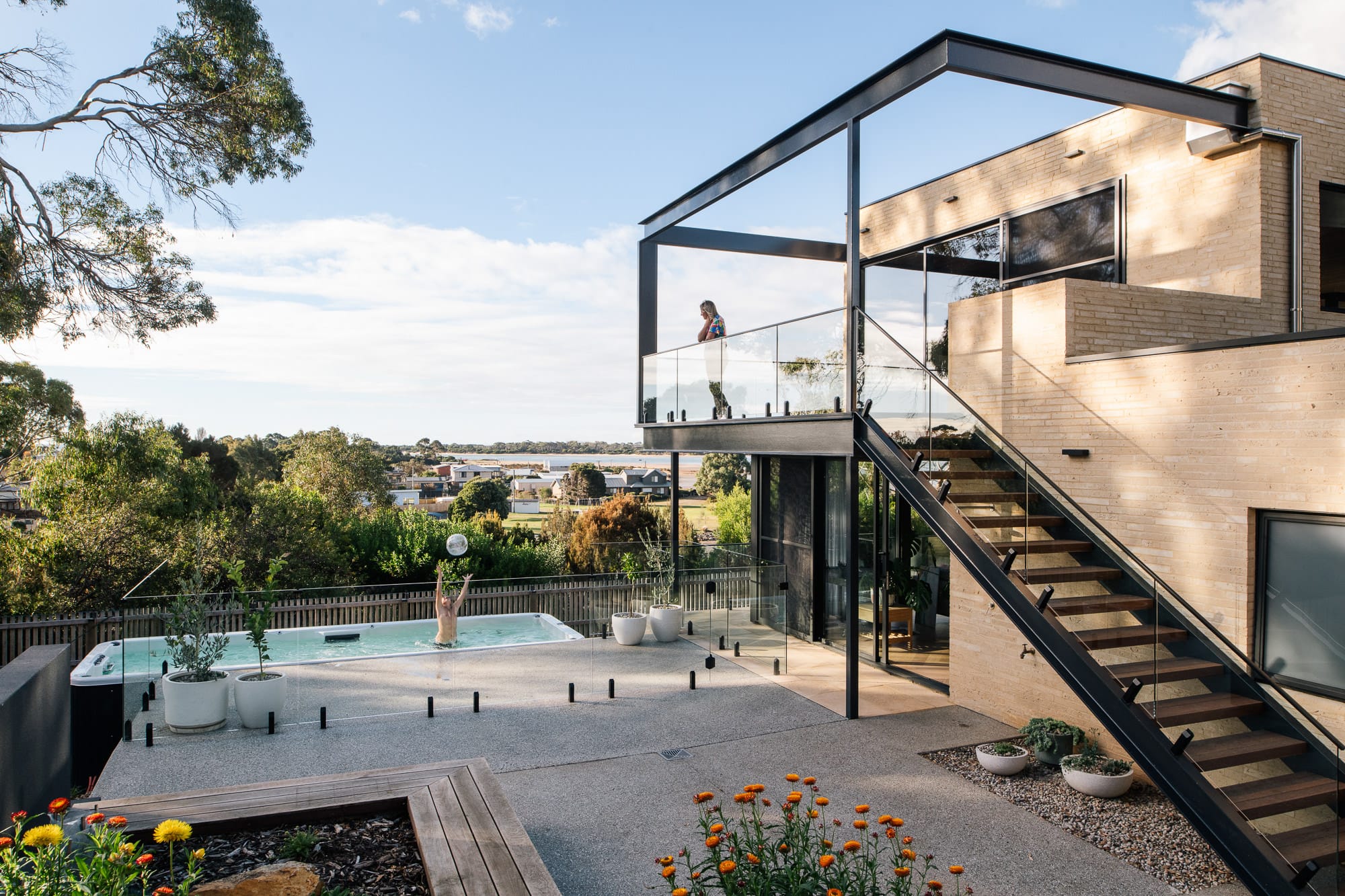 Mortlock Timber Series: The Milldam. Photography by Anjie Blair. Rear facade of double storey residential home with large external staircase leading to balcony, overlooking pool. 