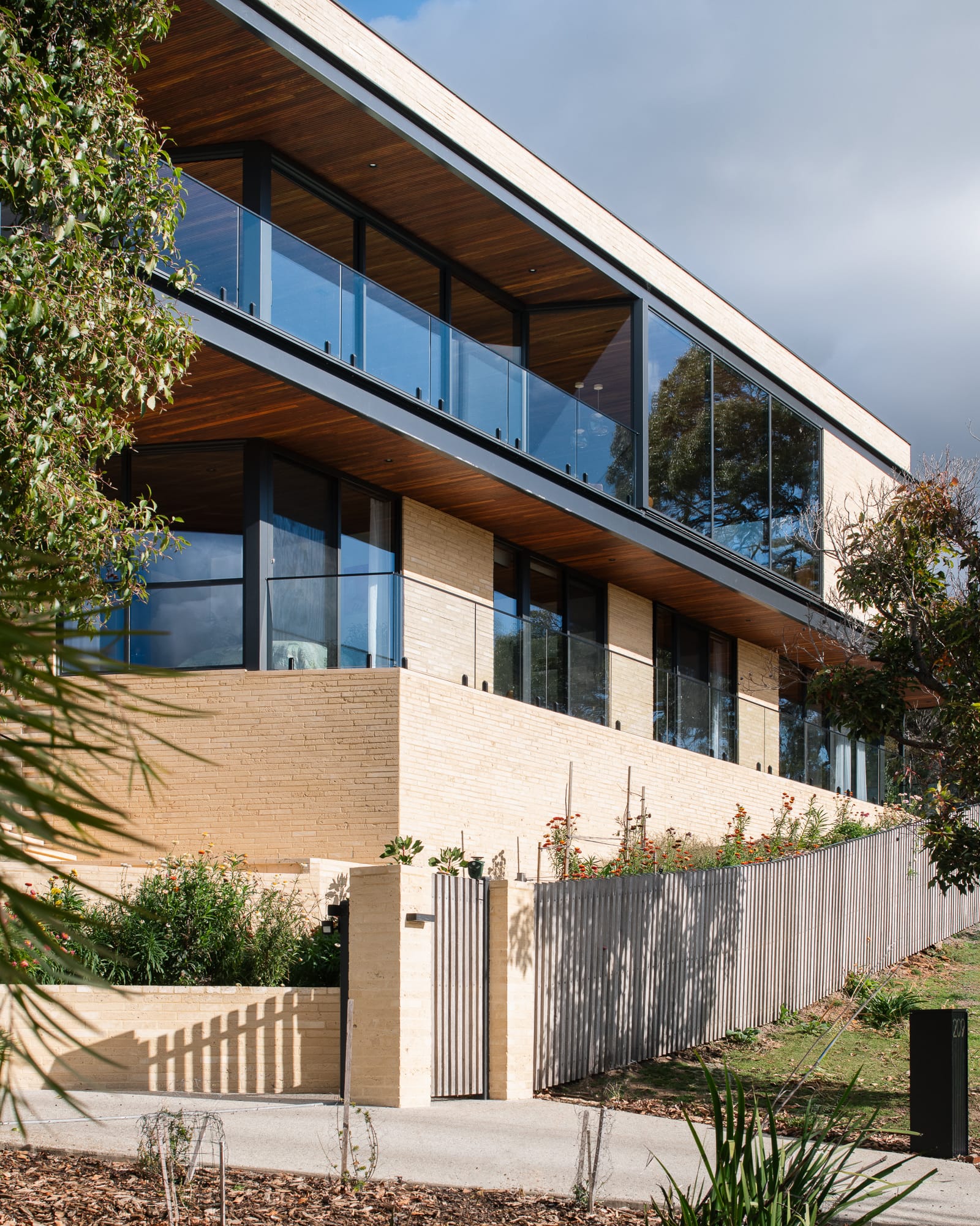 Mortlock Timber Series: The Milldam. Photography by Anjie Blair. Multi-storey residential home constructed with light brick and warm timber. Floor-to-ceiling windows, doors and large balconys. 