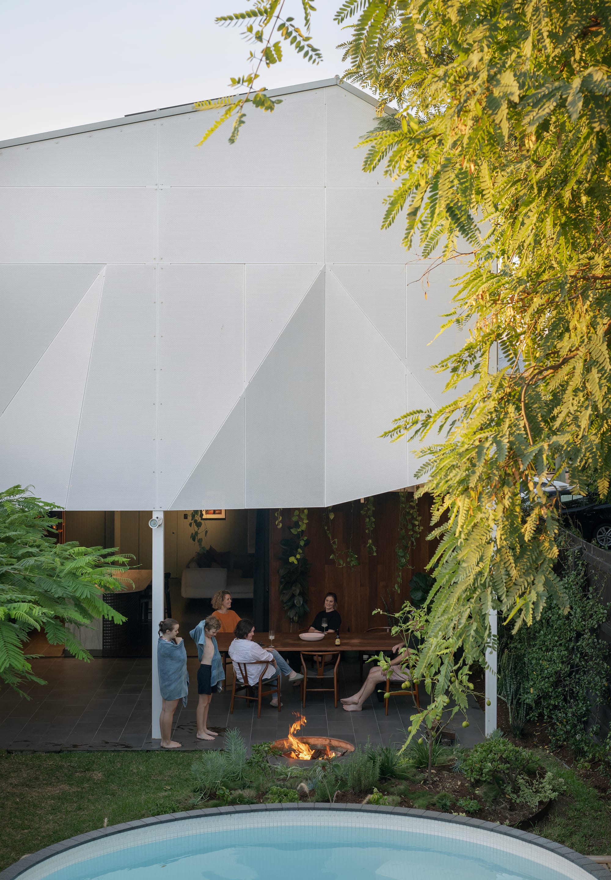 Outdoor timber dining table on bluestone patio, overlooking green grass backyard. 