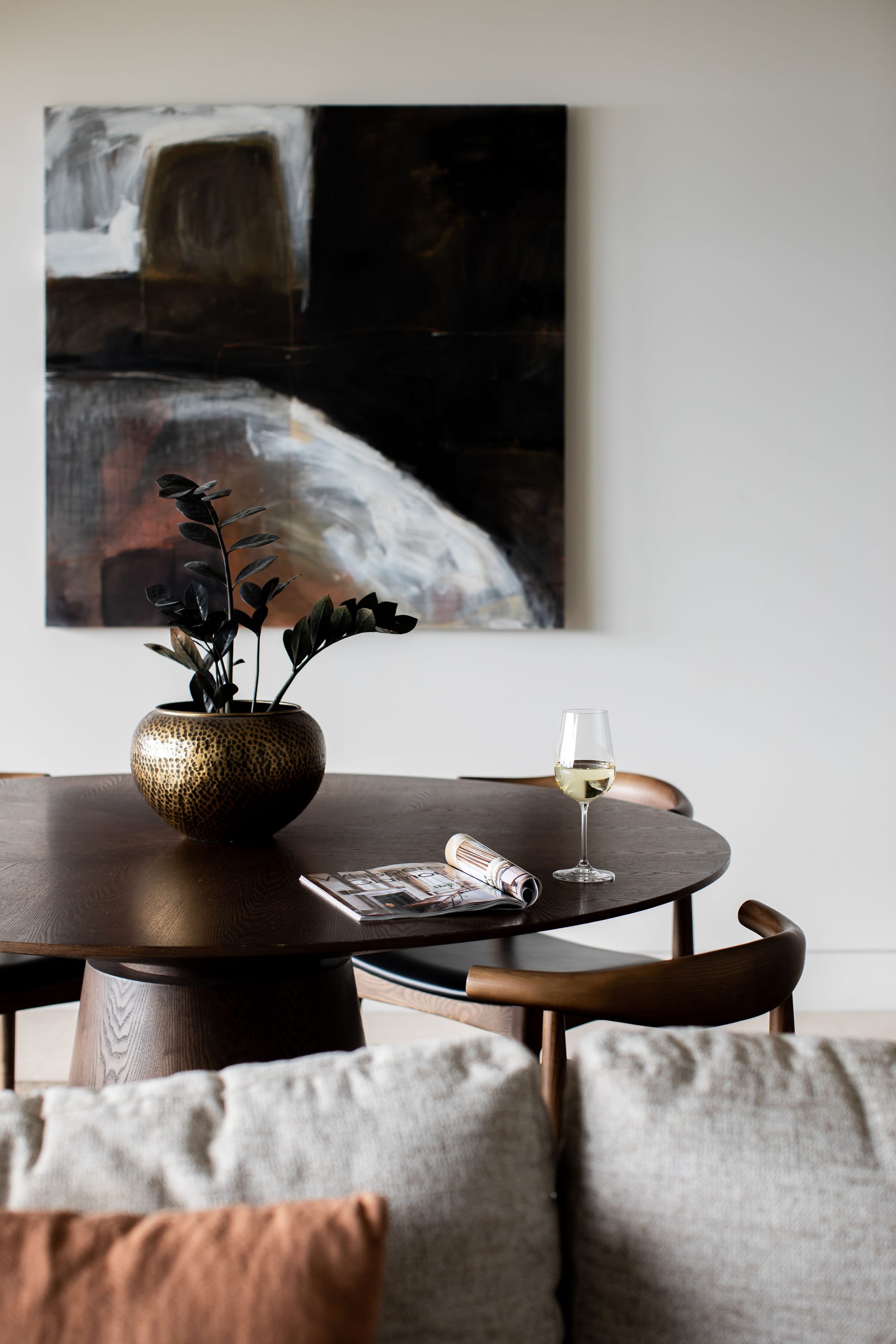 Amarna Luxury Beach Resort. Photography by Will Salkeld. Round timber dining table behind grey modular lounge. Abstract print on white wall in background. 