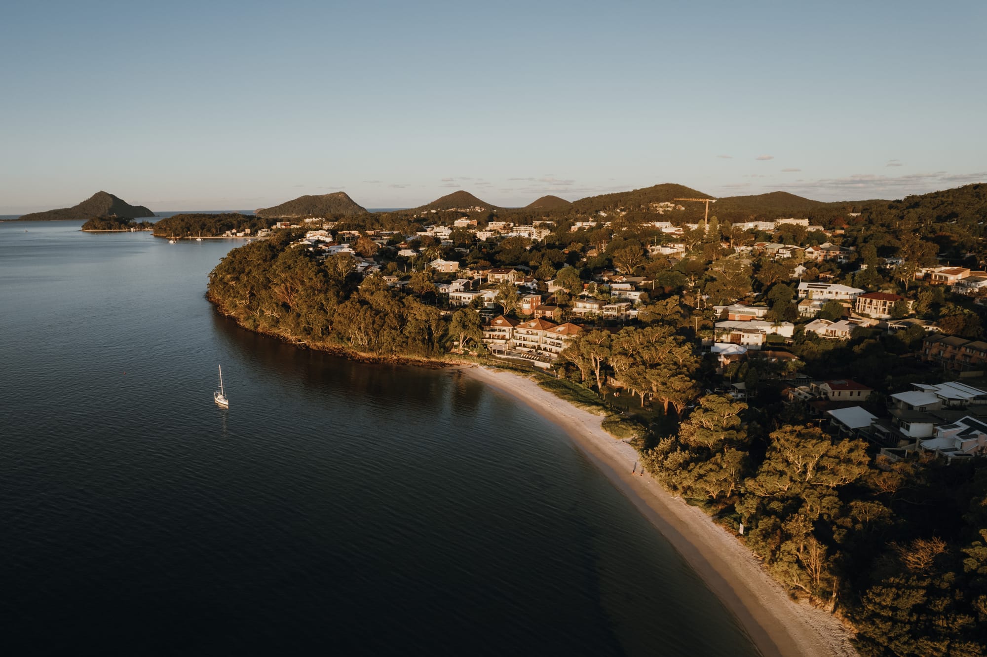 Amarna Luxury Beach Resort. Photography by Will Salkeld. Aerial view of coastline with dense foliage and large multi-story structure on the beach. 