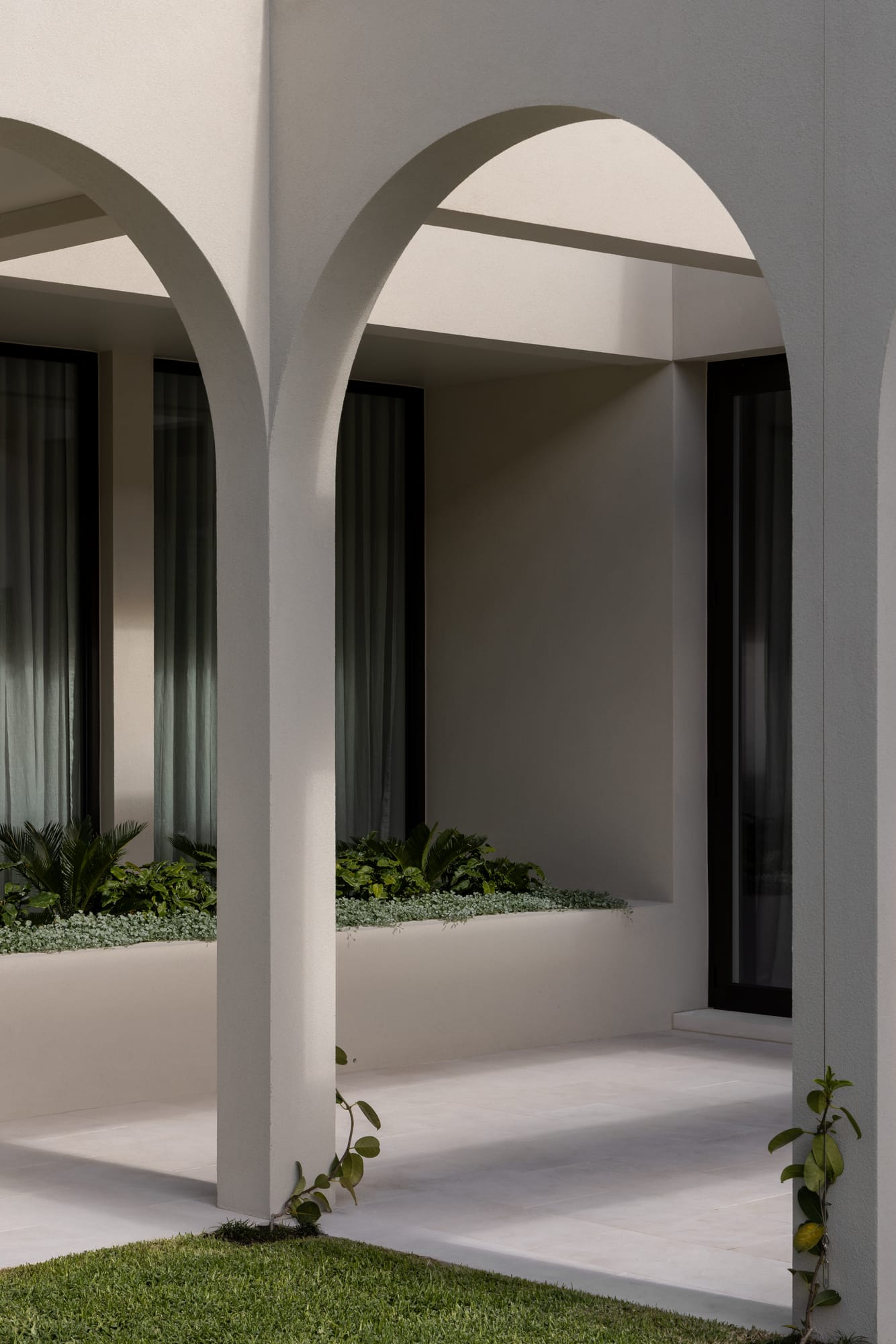 An exterior shot of grey rendered archways and a landscaped planter