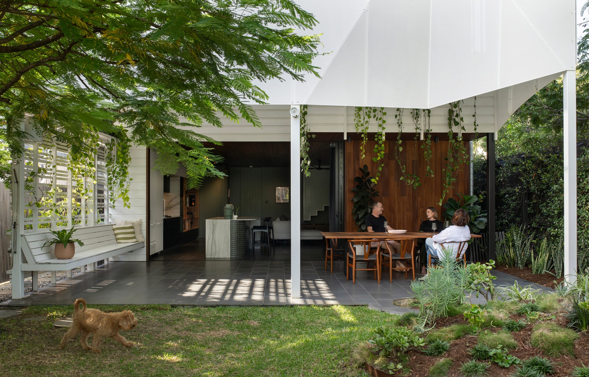 Cornerstone by Loupe Architecture. Photography by Alanna Jayne McTiernan. Outdoor patio with geometric white steel screen ceiling and roof. Green grass, gardens and leafy gardens. 