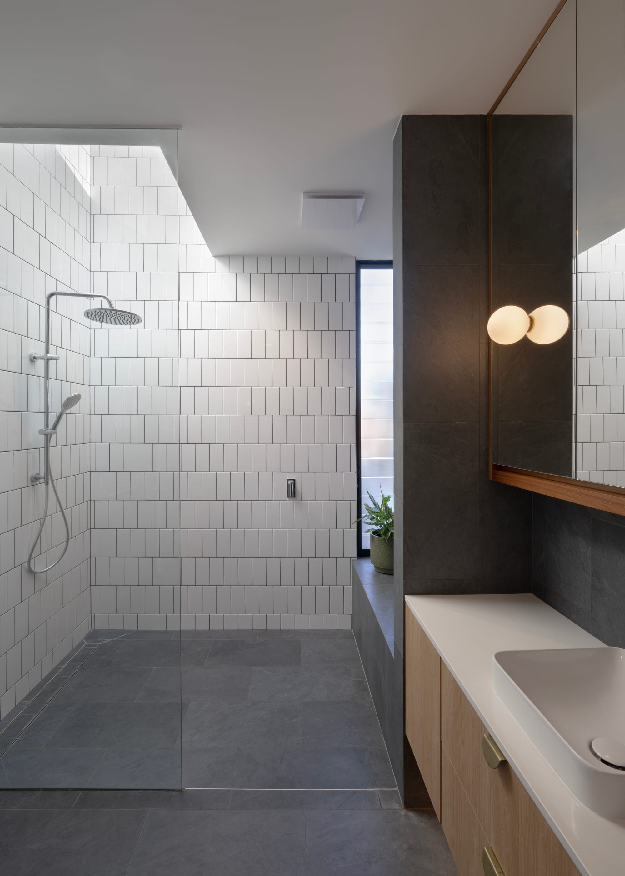 Cornerstone by Loupe Architecture. Photography by Alanna Jayne McTiernan. Bathroom with white subway tiles up walls, bluestone tiles on floors and walls, white and timber vanity. 