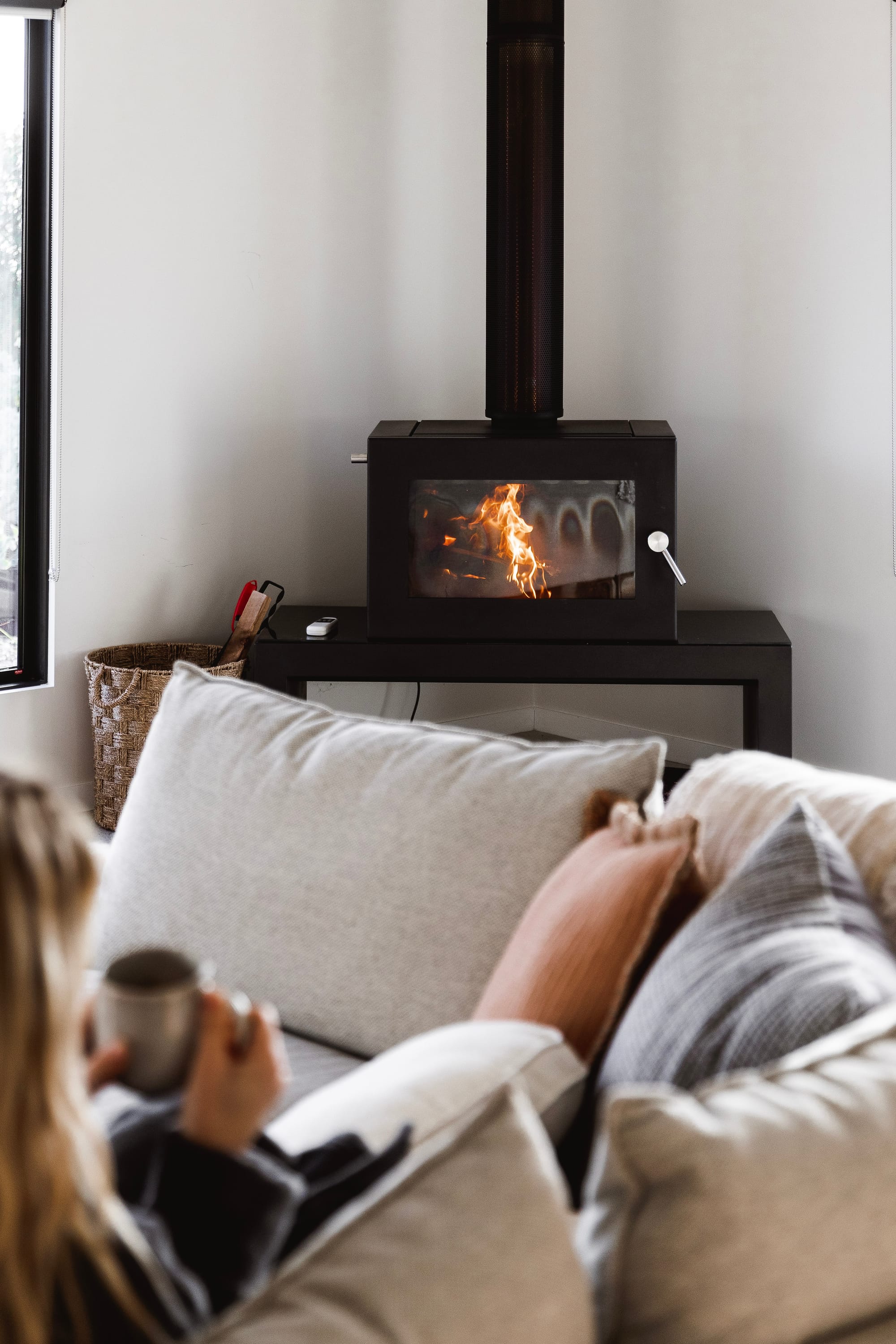 Forrest Haus Retreat. Images copyright of Forrest Haus Retreat. Black steel woodfire in corner of white walled room behind grey modular couch. 