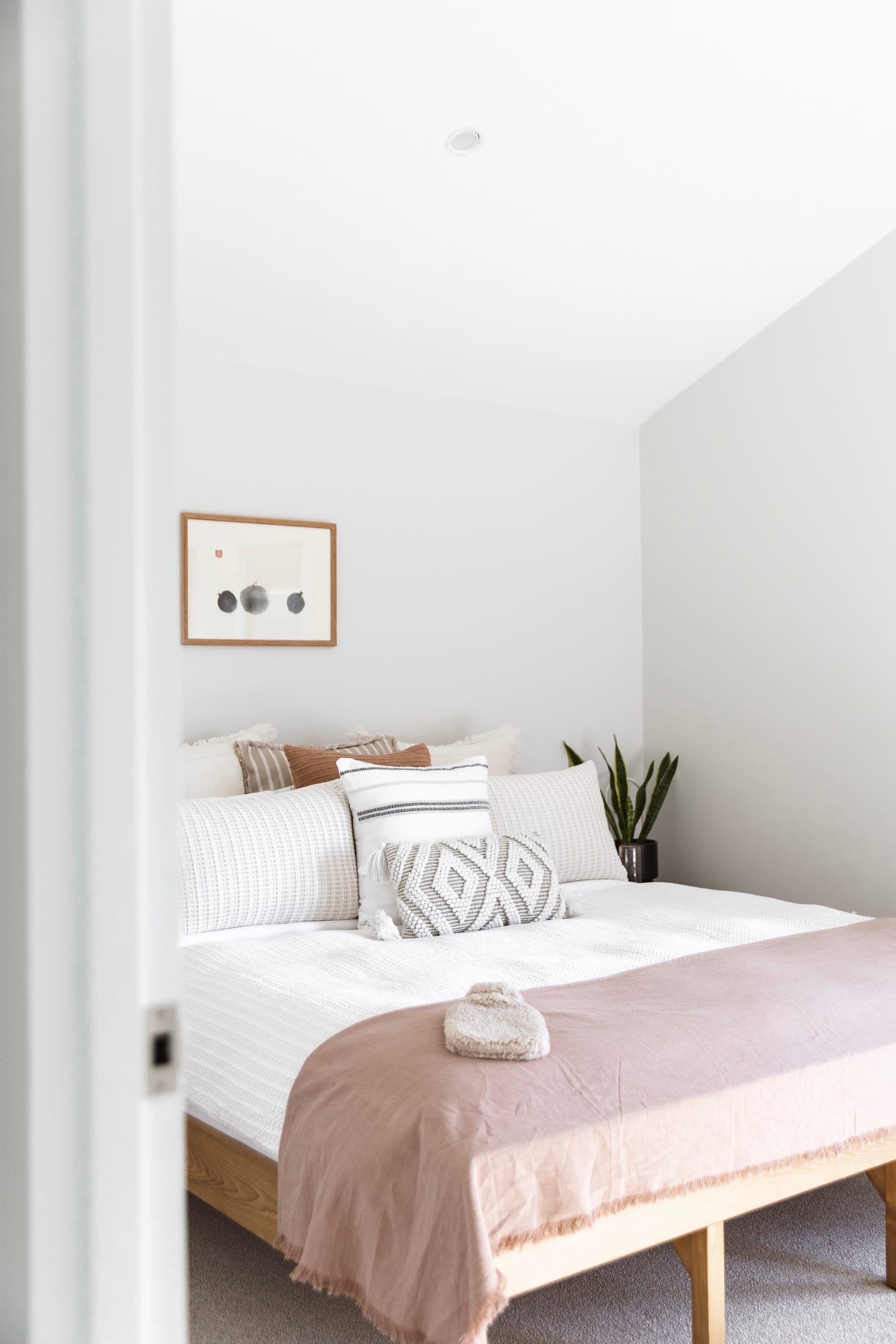 Forrest Haus Retreat. Images copyright of Forrest Haus Retreat. Bedroom with high, white walls and ceilings. Timber bed frame with white sheets and pink linen throw rug. 