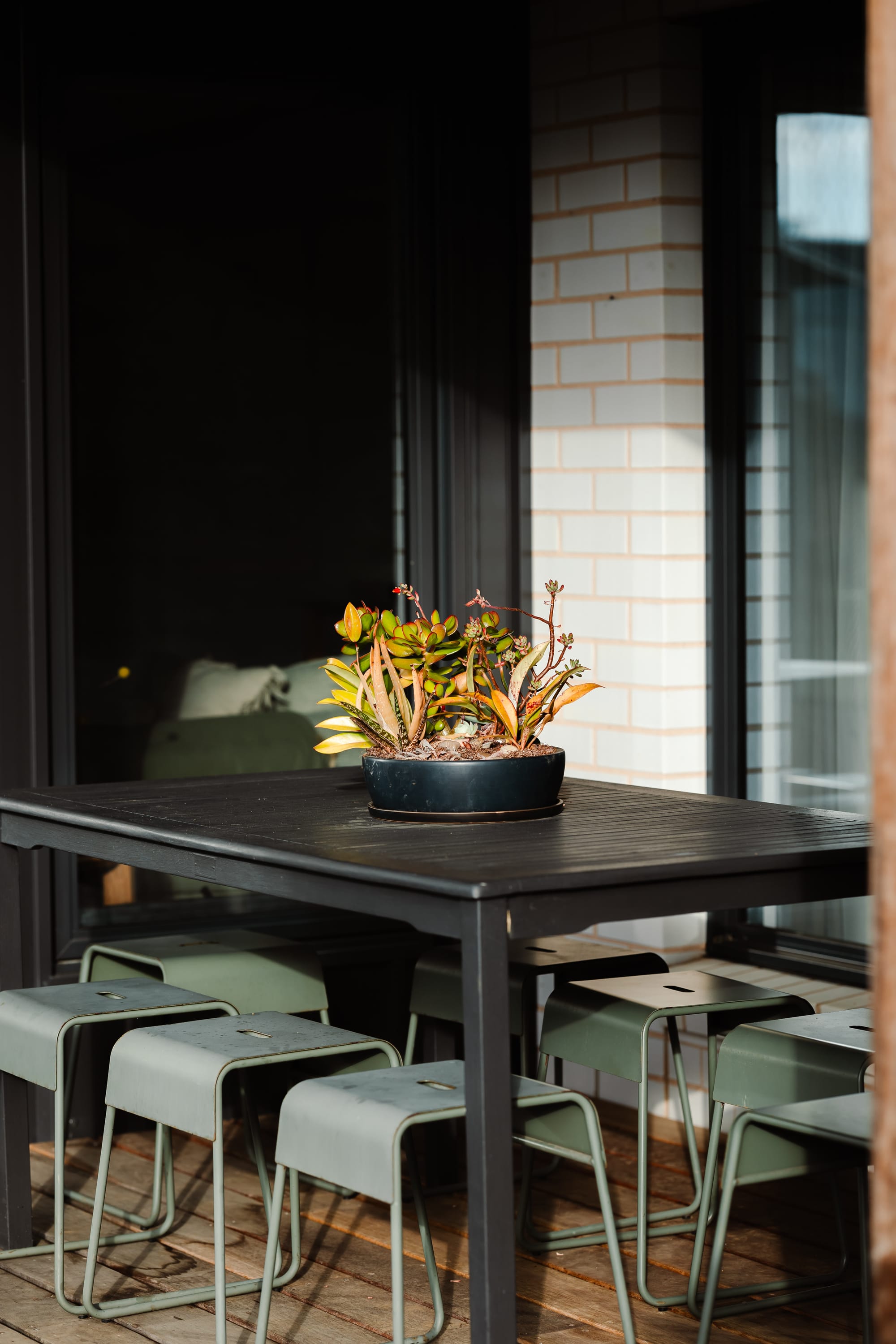 Forrest Haus Retreat. Images copyright of Forrest Haus Retreat. Black outdoor dining table with succulents in centre and green steel stools. 