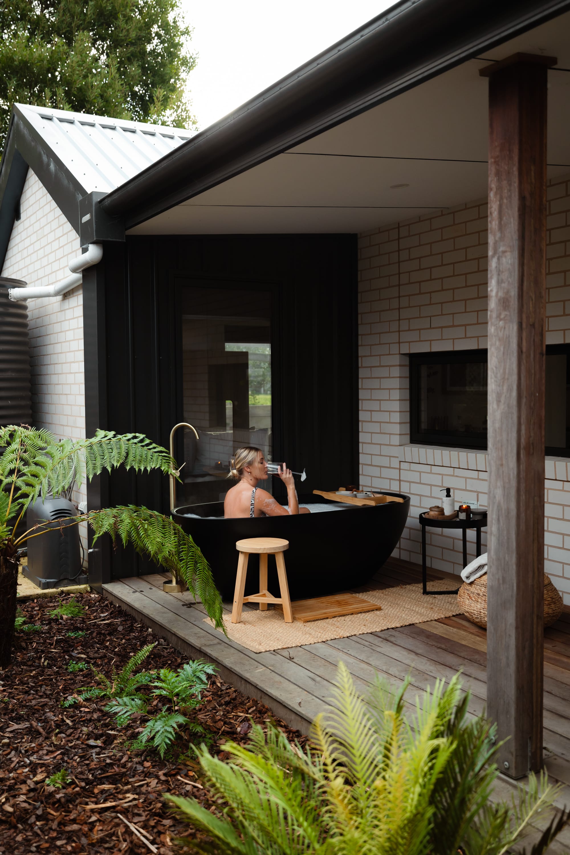 Forrest Haus Retreat. Images copyright of Forrest Haus Retreat. An exterior shot showing the outdoor bath with a woman drinking a glass of wine