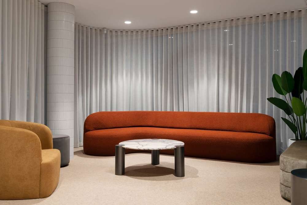 An interior image of an office waiting room with designer couches