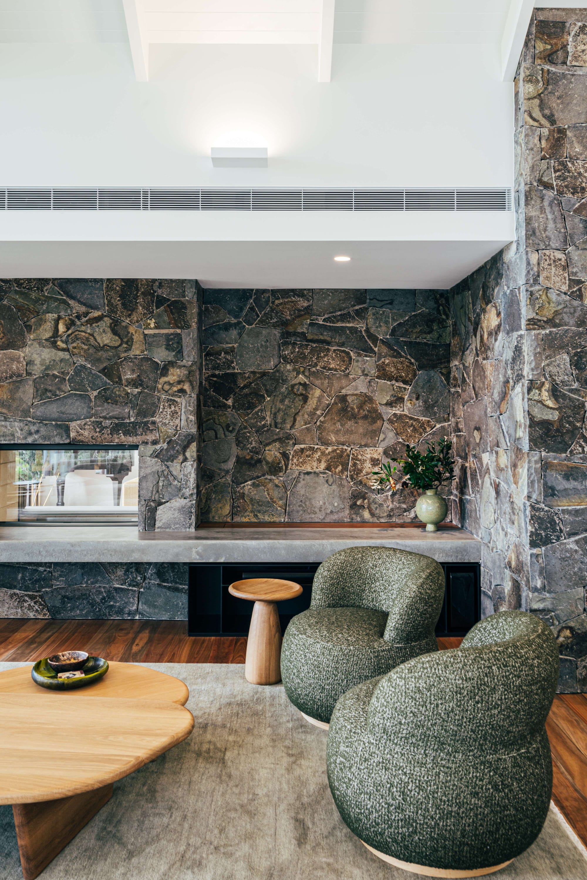 Project 465 by Robertson Collectif. Photography by Anna Mul. Slate stone walls in living space, with timbre floorboards and abstract grey bubble armchairs.