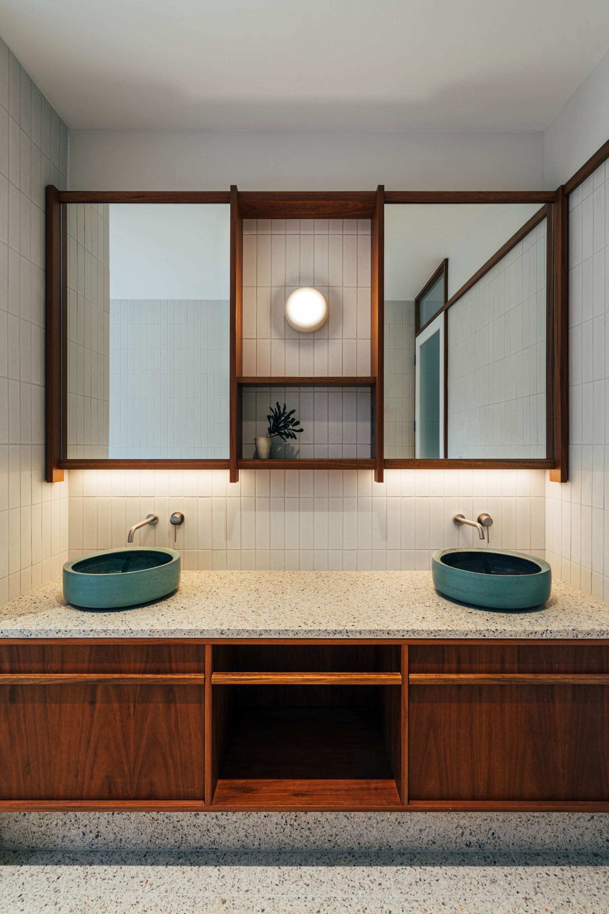 Project 465 by Robertson Collectif. Photography by Anna Mul. Bathroom with terrazzo flooring and countertops. Timber cabinetry, white tile splashback and teal round above-counter sinks.