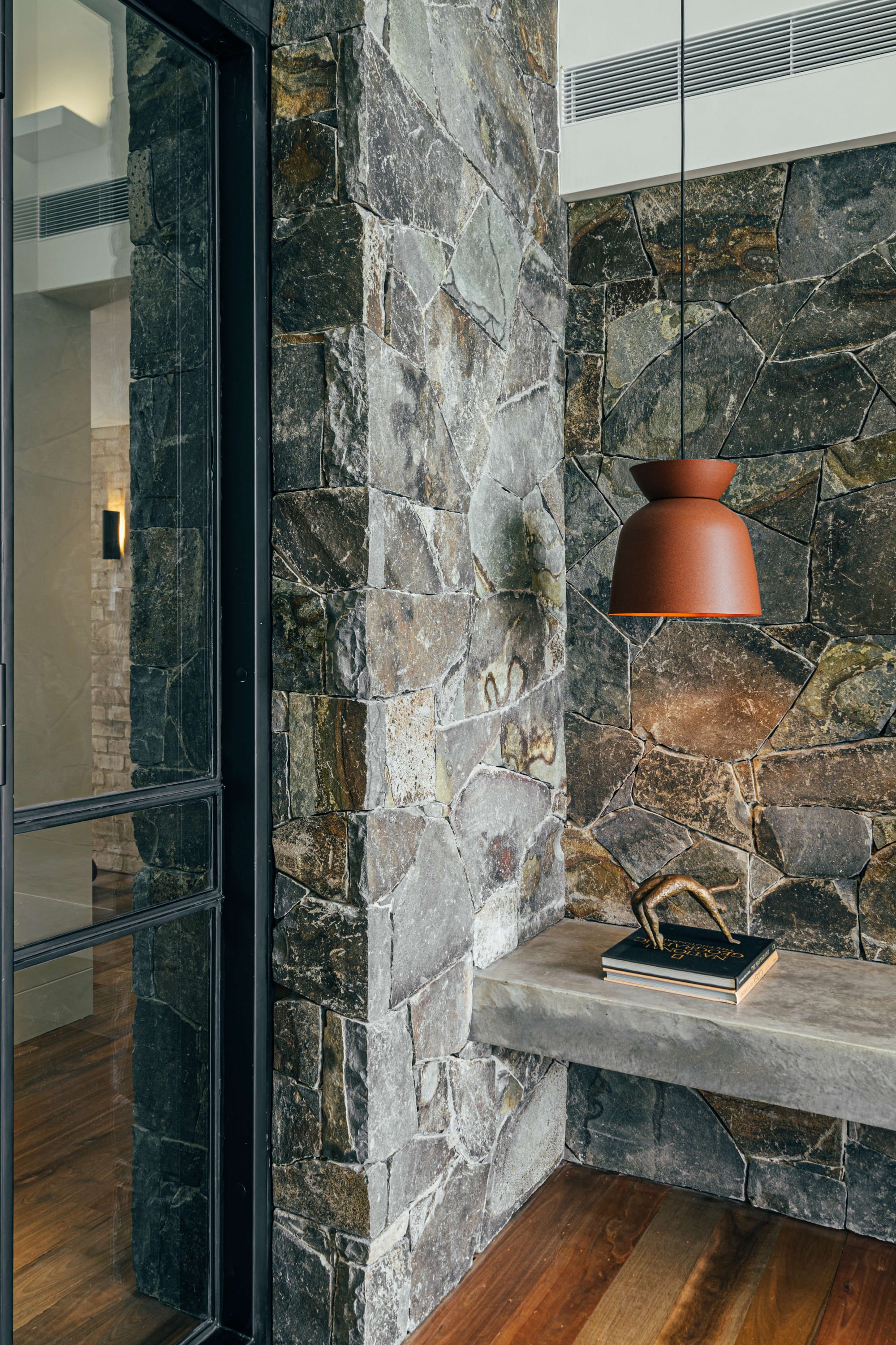 Project 465 by Robertson Collectif. Photography by Anna Mul. Slate stone walls with concrete floating bench. Terracotta coloured pendant light.