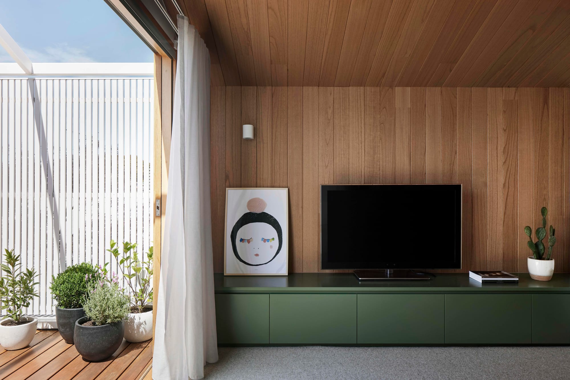 Rosie by Eckersley Architects. Photography by Tess Kelly. Timber walled living space with green cabinetry and timber deck outside. 