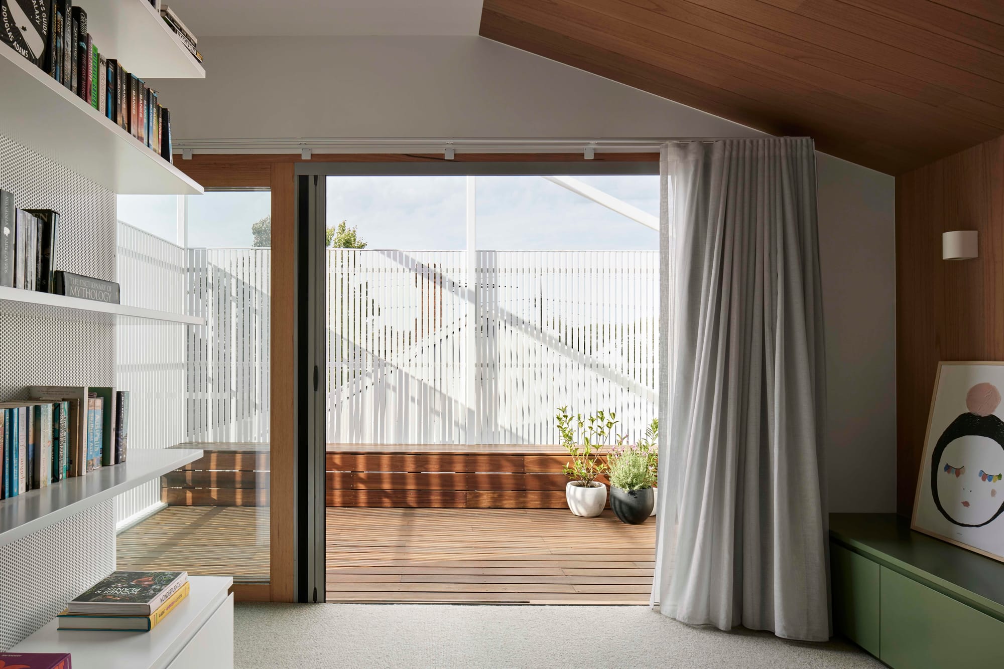 Rosie by Eckersley Architects. Photography by Tess Kelly. Timber framed sliding door leading to outdoor terrace with timber decking and white screening. 