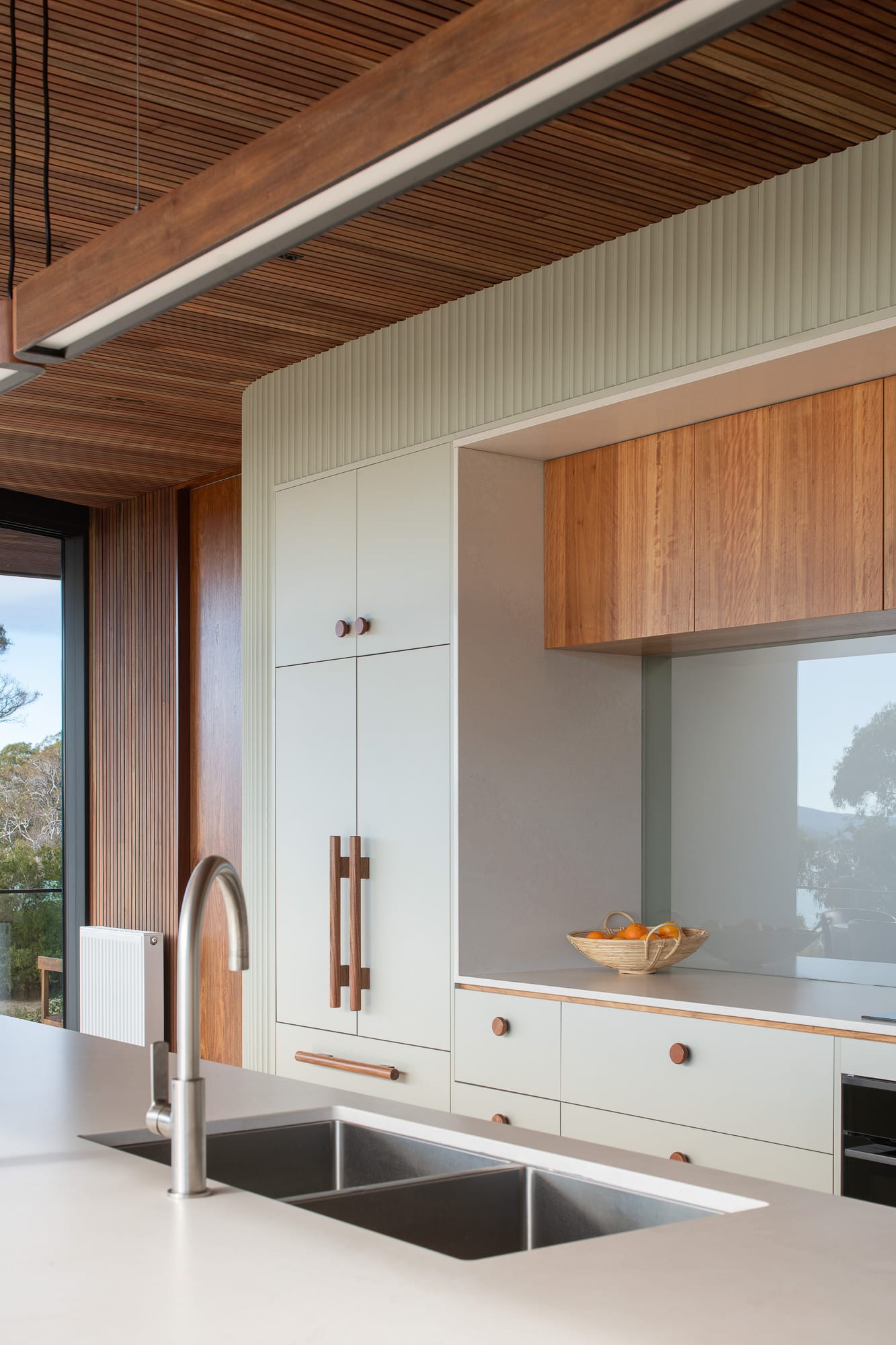 Mortlock Timber Series: The Milldam. Photography by Anjie Blair. Hallway with light timber herringbone floors, dark timber clad walls, and a large open void with rubber plant growing in gap. 