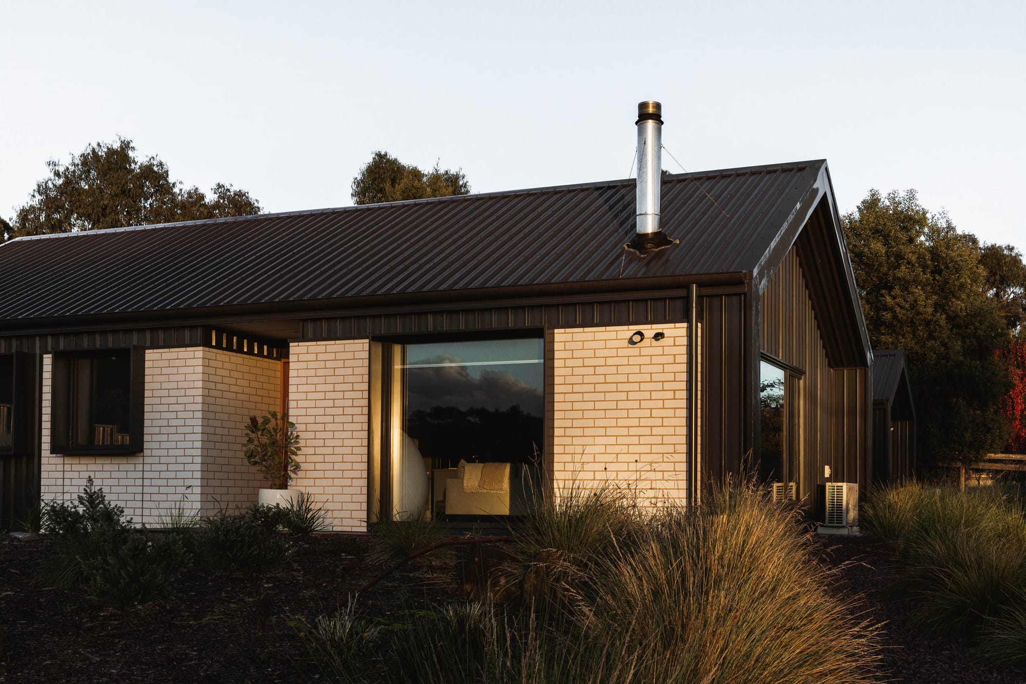 Forrest Haus Retreat. Images copyright of Forrest Haus Retreat. An exterior shot showing the retreat at sunset with a warm glow on the white brick walls