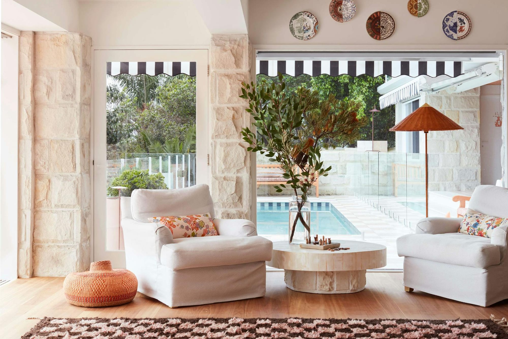 La Palma by YSG Studio. Living room featuring chequered carpet and limestone wall and pool view