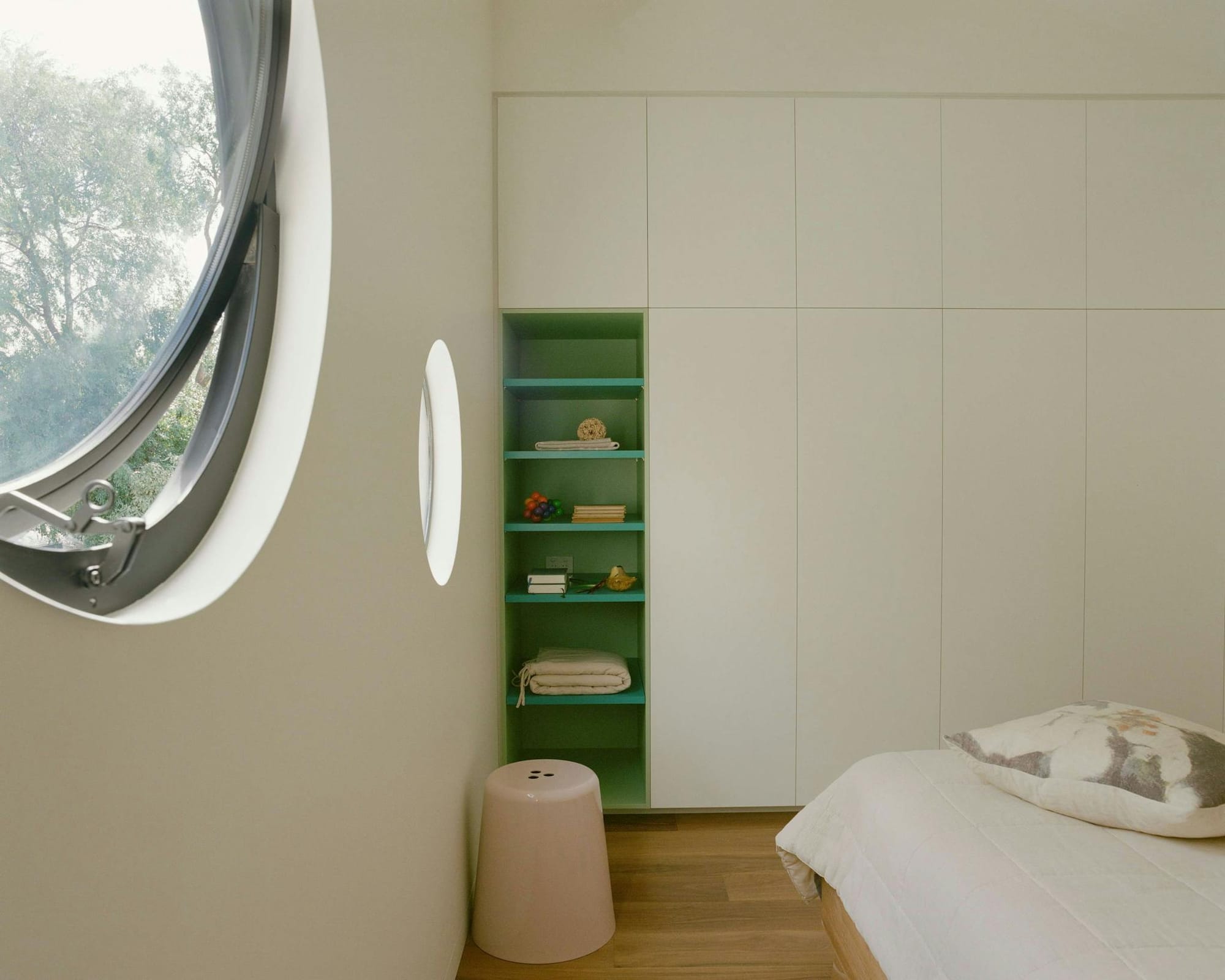 Northcote Hacienda by Hindley & Co., Bedroom with round windows with fitted wardrobe and green shelf and salt and pepper seat