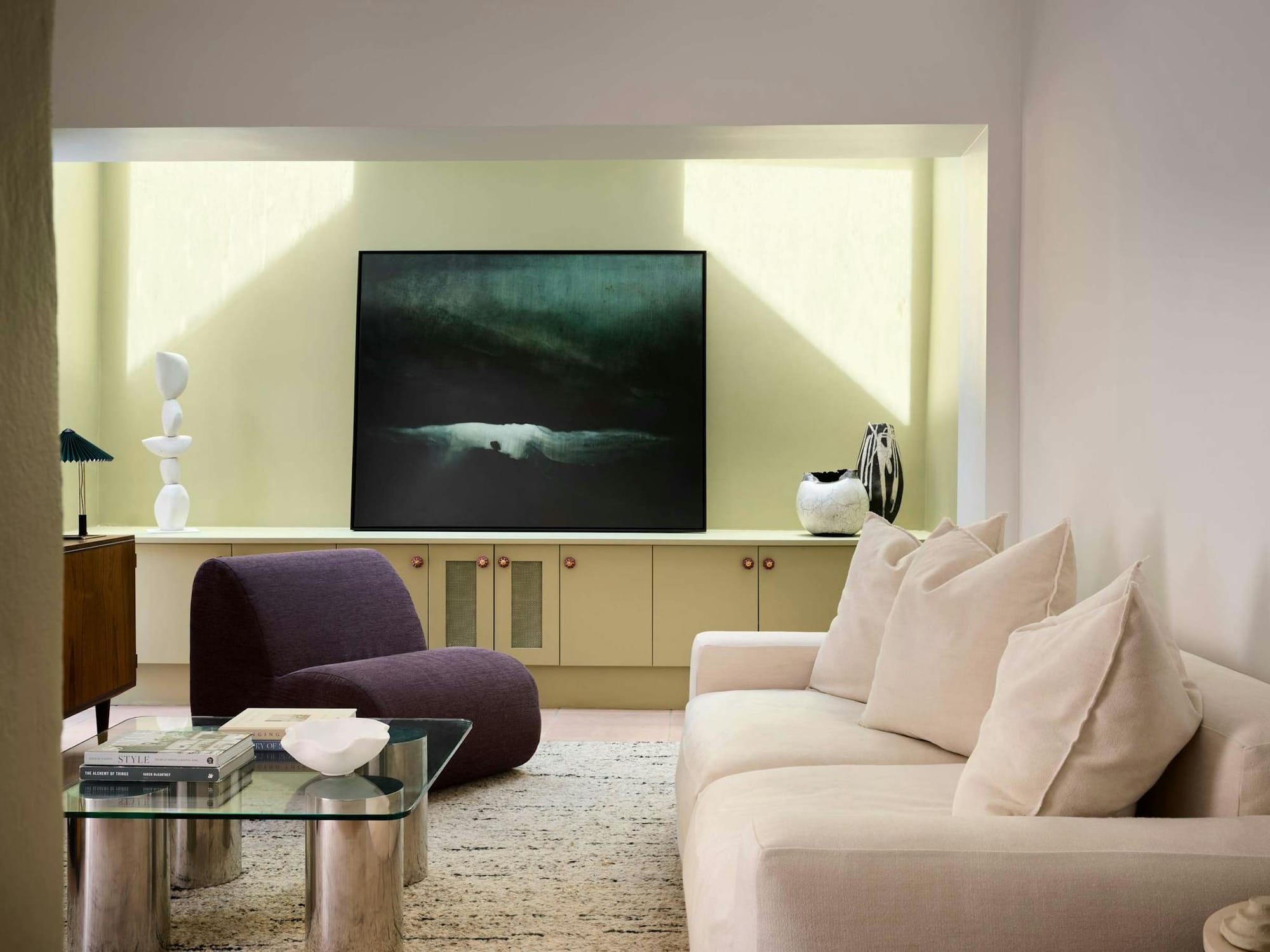 Chapel House by Furnished. Living room view with pastel color interior, featuring glass table and purple armchair.